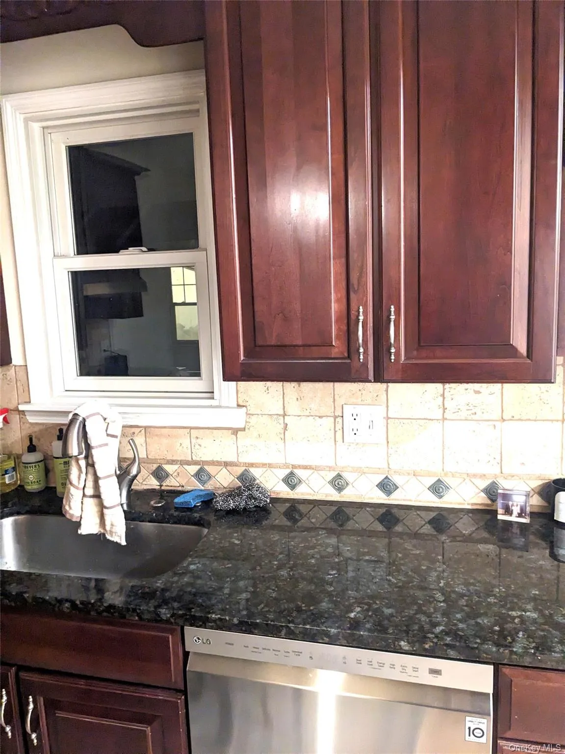 Interior details with tasteful backsplash, stainless steel dishwasher, dark stone countertops, and sink Interior details with tasteful backsplash, stainless steel dishwasher, dark stone countertops, and sink