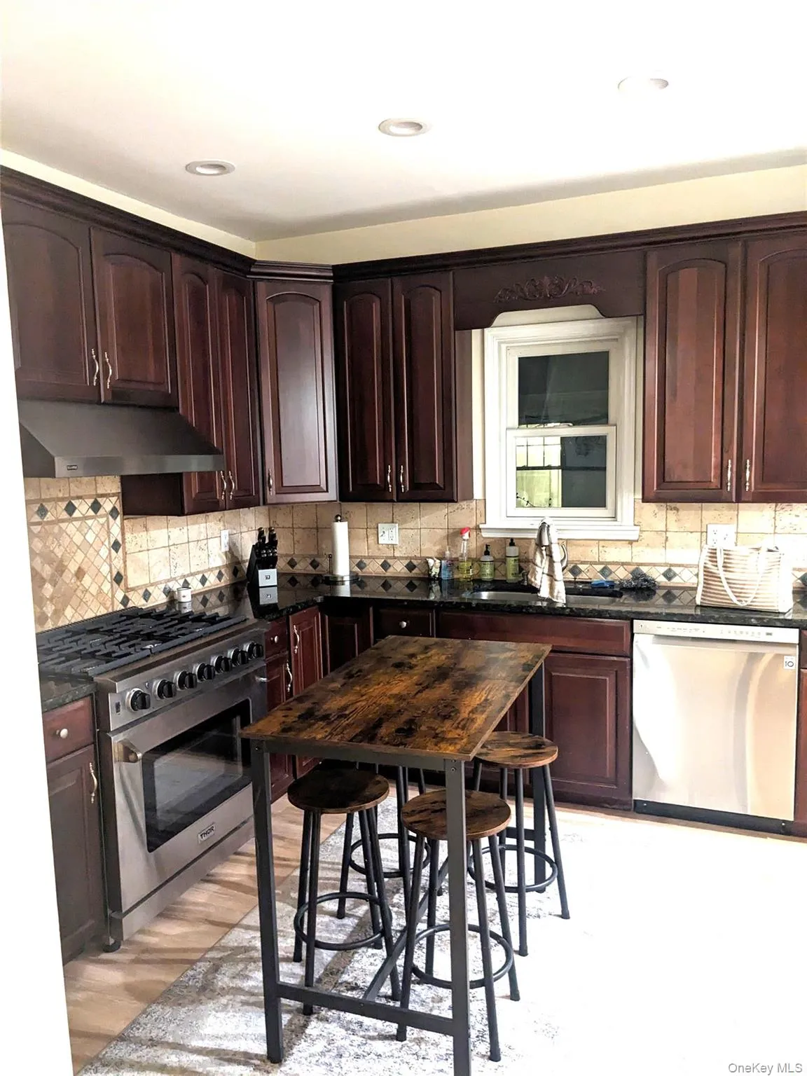 Kitchen with tasteful backsplash, sink, stainless steel appliances, and light hardwood / wood-style floors Kitchen with tasteful backsplash, sink, stainless steel appliances, and light hardwood / wood-style floors