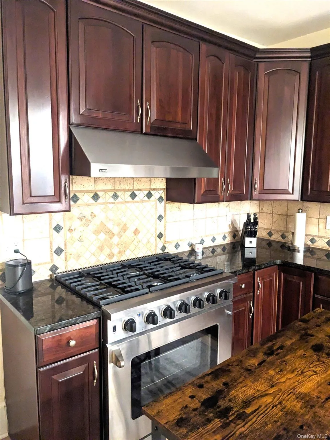 Kitchen featuring backsplash, high end stainless steel range, and dark stone countertops Kitchen featuring backsplash, high end stainless steel range, and dark stone countertops