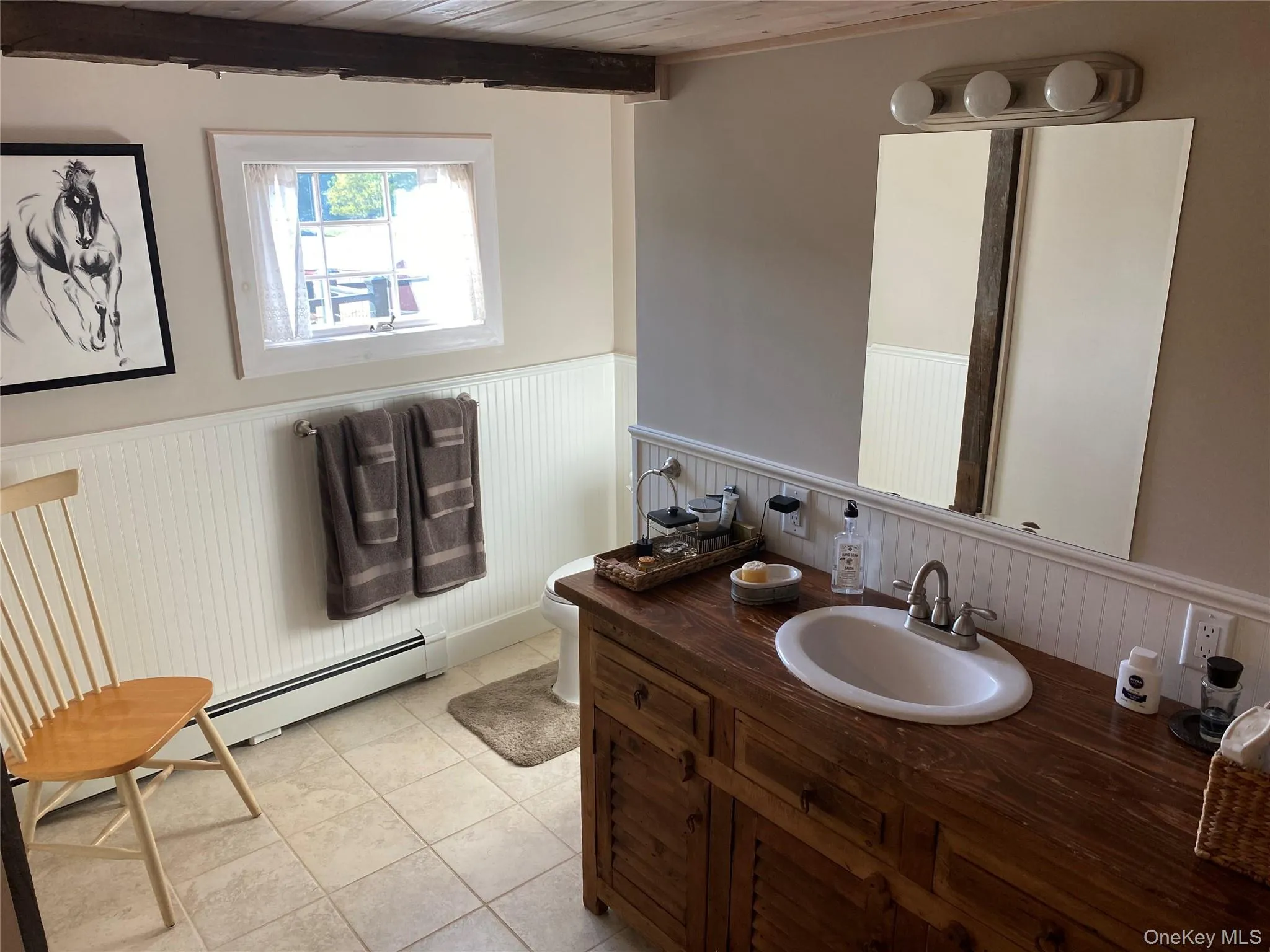 Bathroom with wainscoting, vanity, a wood ceiling with exposed beams, and light tile patterned floors Bathroom with wainscoting, vanity, a wood ceiling with exposed beams, and light tile patterned floors