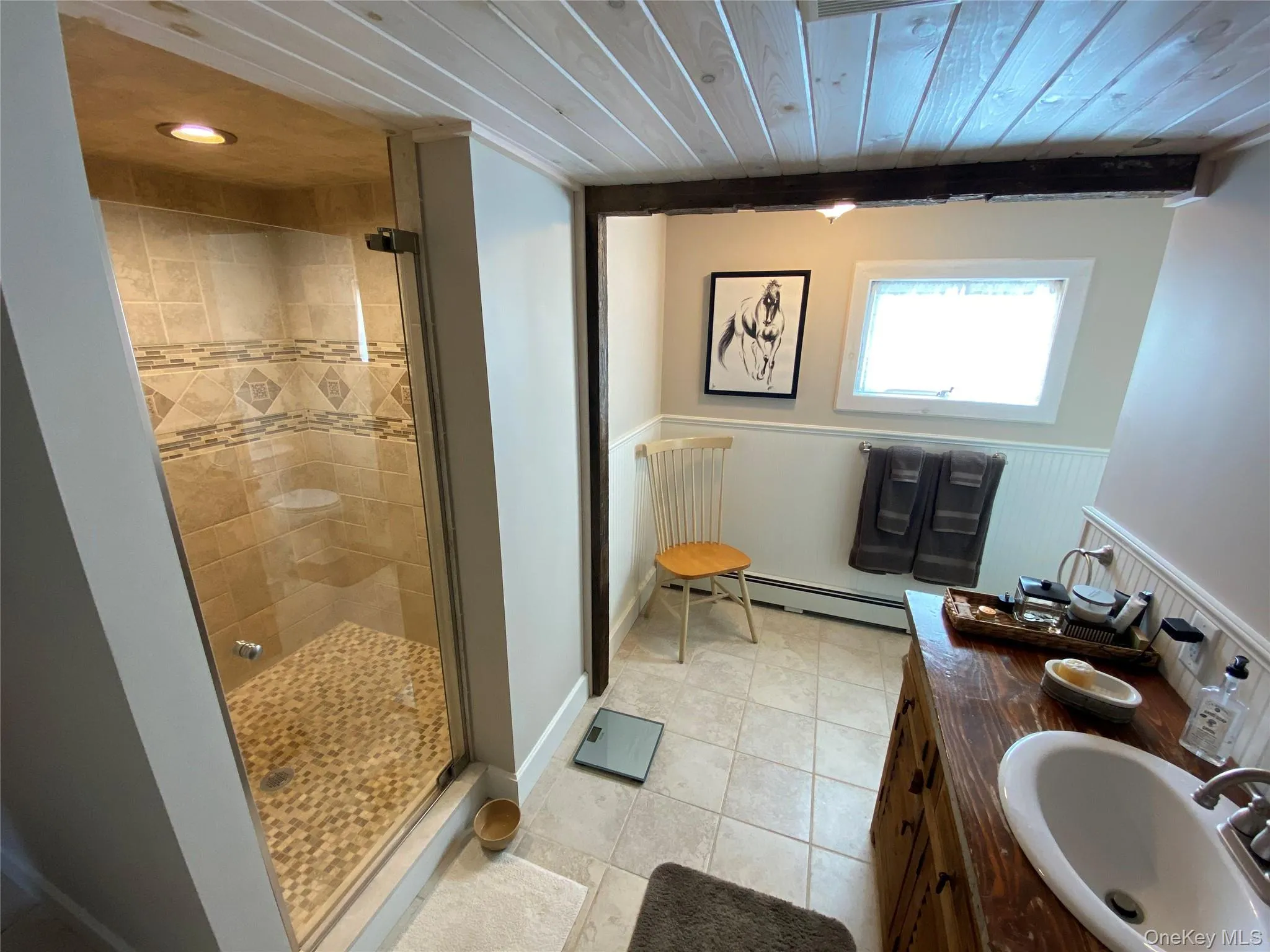Full bathroom with a stall shower, vanity, light tile patterned floors, and baseboard heating Full bathroom with a stall shower, vanity, light tile patterned floors, and baseboard heating
