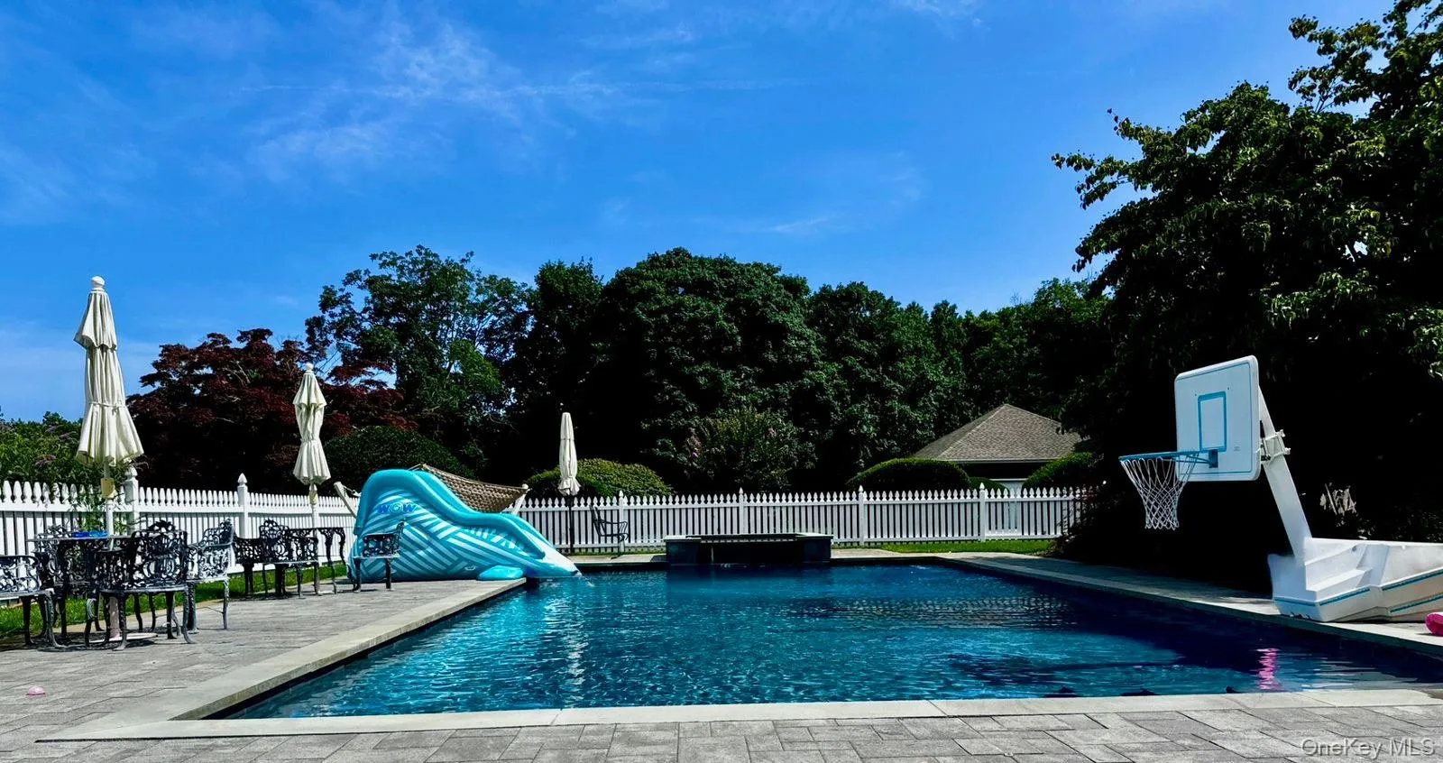 View of pool featuring a water slide, a patio area, and a pool with connected hot tub View of pool featuring a water slide, a patio area, and a pool with connected hot tub