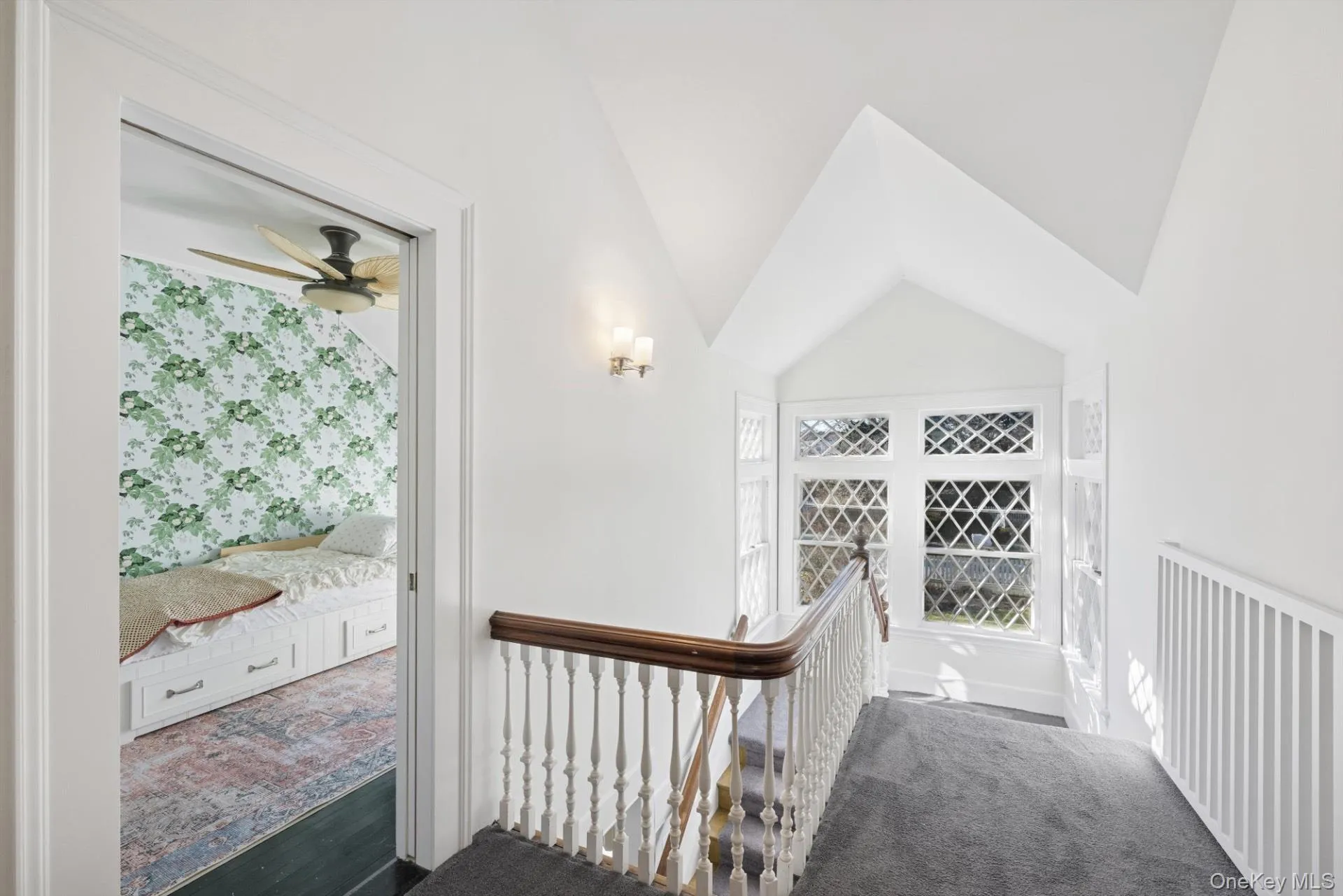 Hallway with vaulted ceiling, an upstairs landing, and dark carpet Hallway with vaulted ceiling, an upstairs landing, and dark carpet