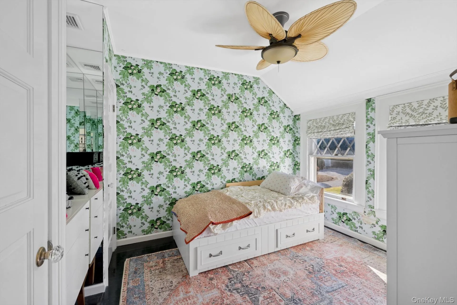 Bedroom with wallpapered walls, vaulted ceiling, ceiling fan, and wood finished floors Bedroom with wallpapered walls, vaulted ceiling, ceiling fan, and wood finished floors