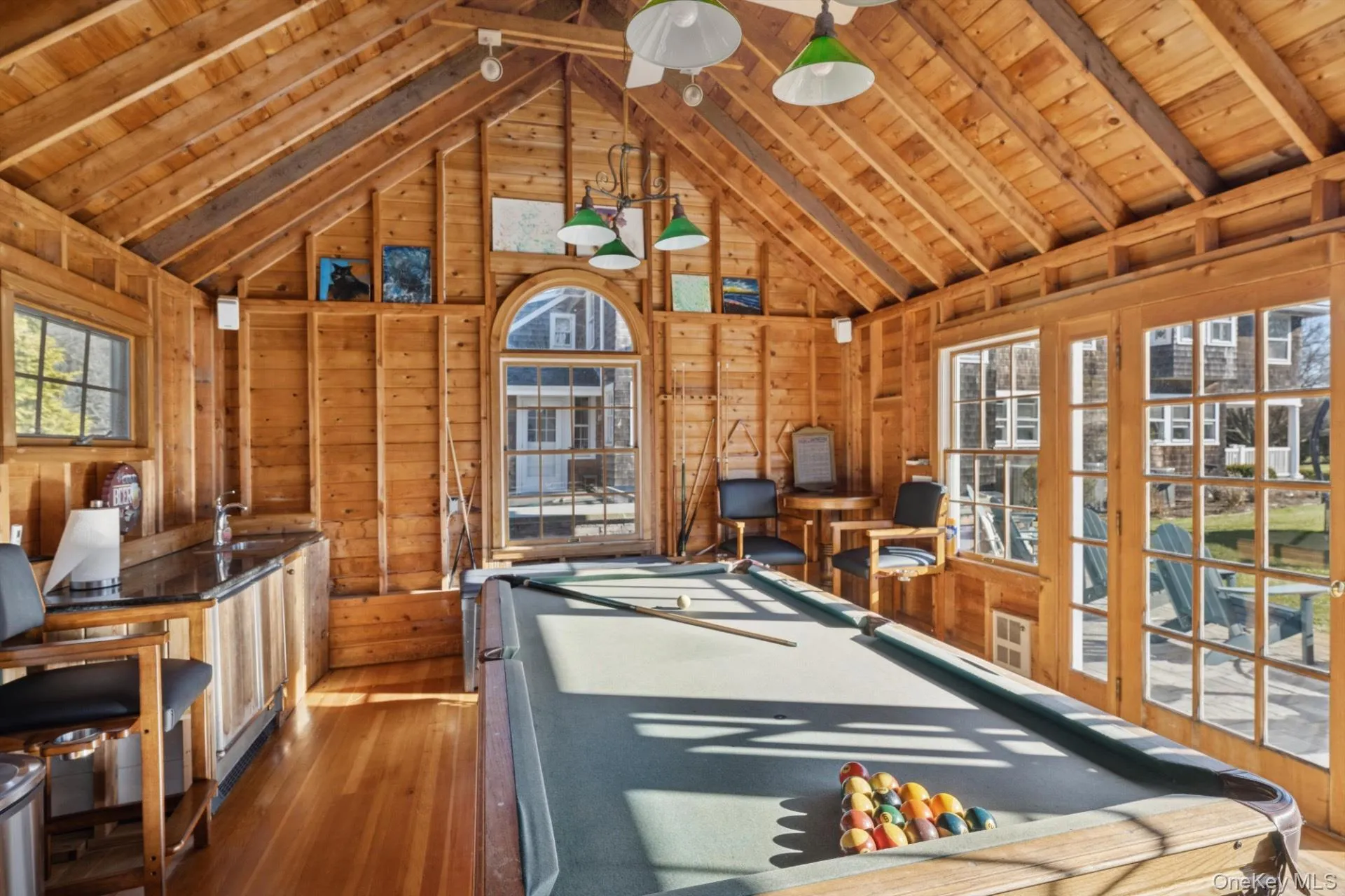 Game room featuring a wooden ceiling with exposed beams, hardwood / wood-style floors, billiards table, high vaulted ceiling, and wood walls Game room featuring a wooden ceiling with exposed beams, hardwood / wood-style floors, billiards table, high vaulted ceiling, and wood walls