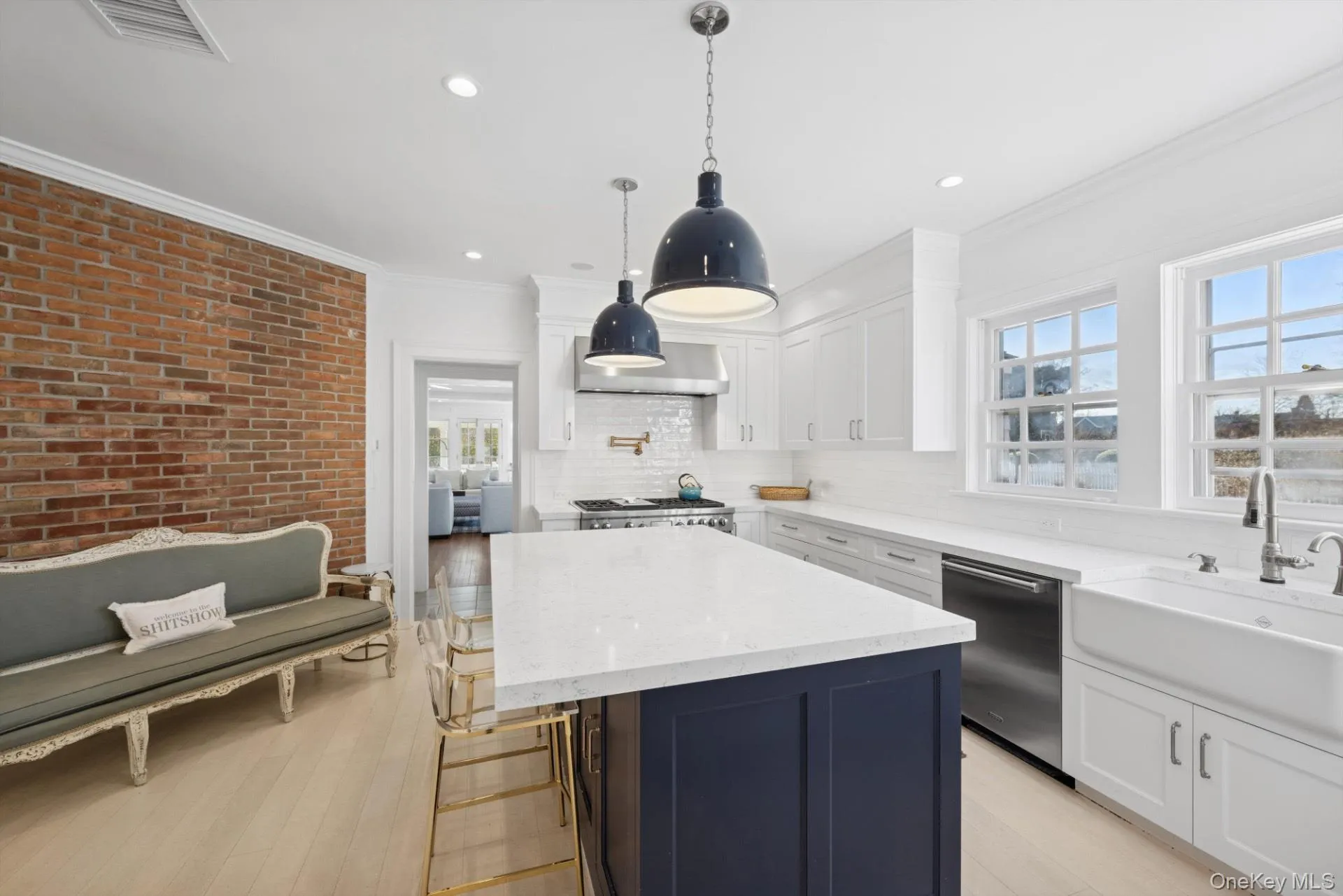 Kitchen featuring light stone counters, white cabinetry, a kitchen island, dishwasher, and decorative light fixtures Kitchen featuring light stone counters, white cabinetry, a kitchen island, dishwasher, and decorative light fixtures