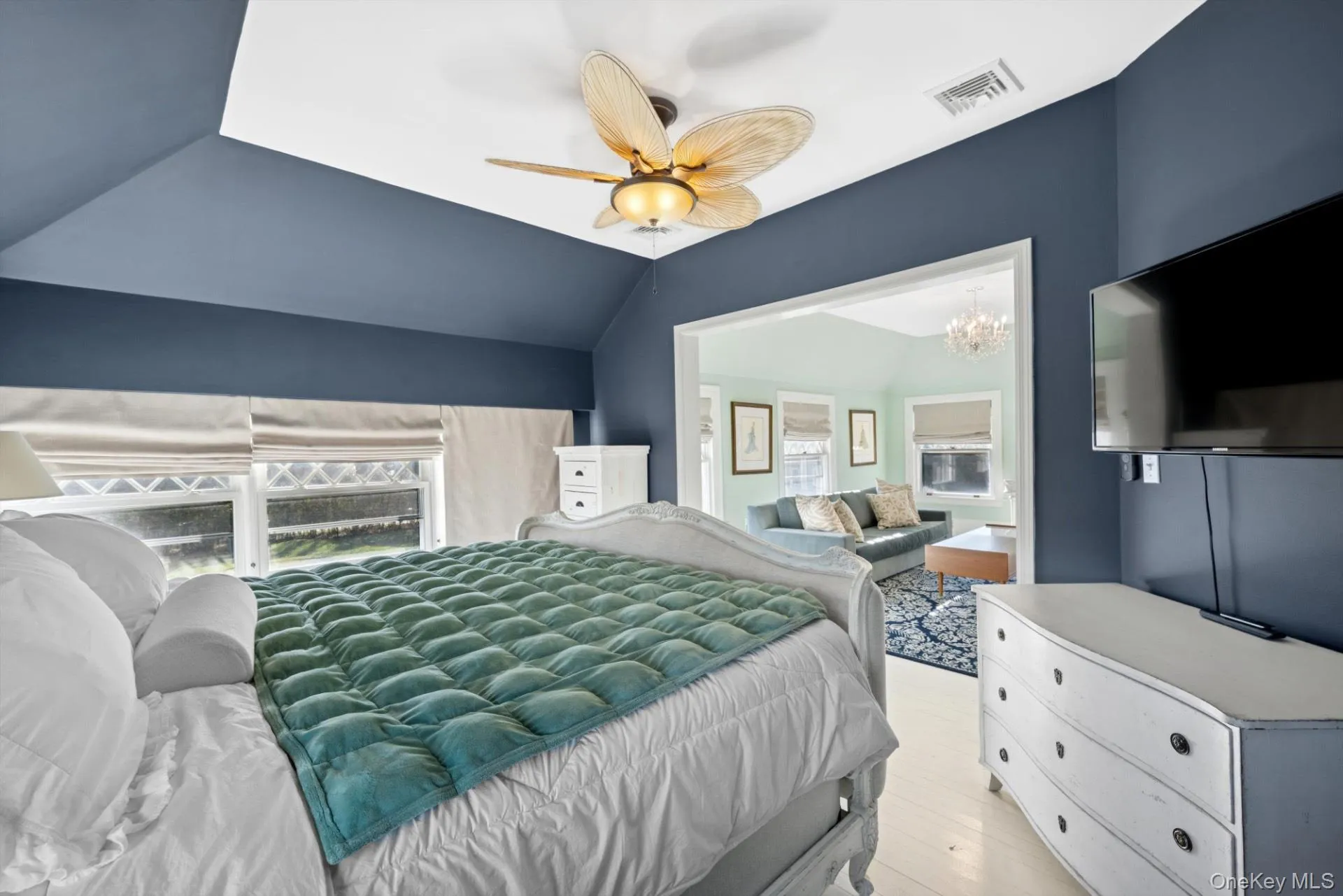 Bedroom with a chandelier, vaulted ceiling, ceiling fan, connected bathroom, and light wood-style floors Bedroom with a chandelier, vaulted ceiling, ceiling fan, connected bathroom, and light wood-style floors