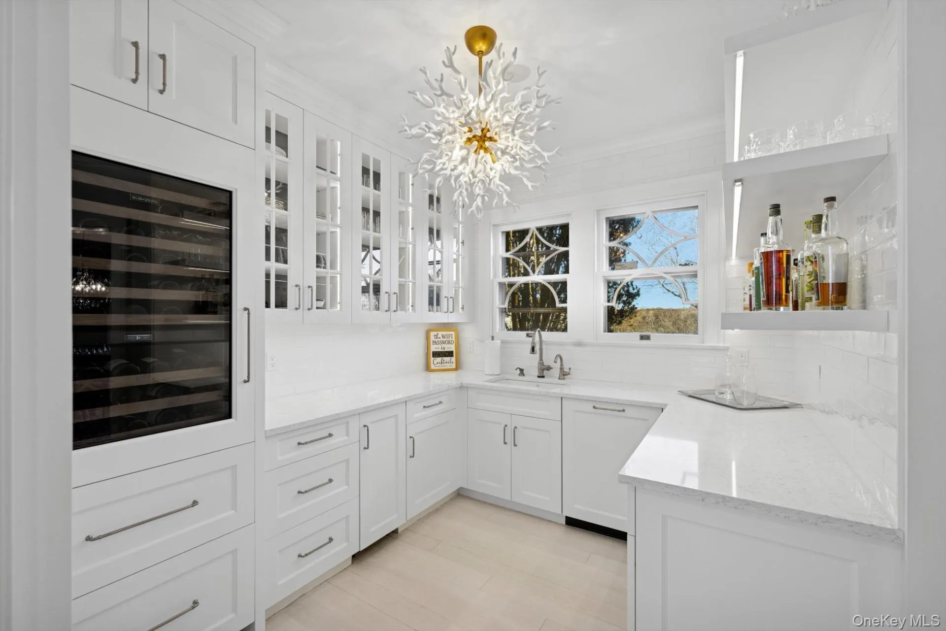 Bar with white cabinetry, light stone counters, beverage cooler, a chandelier, and hanging light fixtures Bar with white cabinetry, light stone counters, beverage cooler, a chandelier, and hanging light fixtures