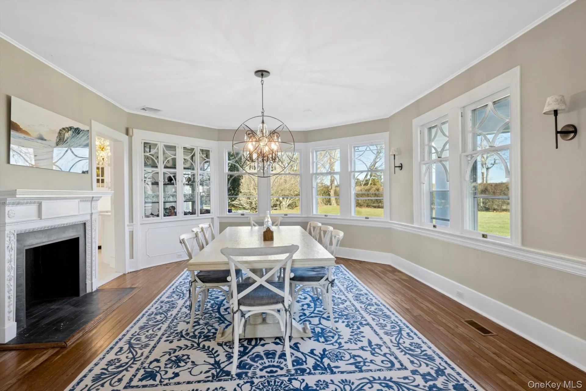 Dining area with a fireplace with flush hearth, dark wood finished floors, crown molding, and a chandelier Dining area with a fireplace with flush hearth, dark wood finished floors, crown molding, and a chandelier