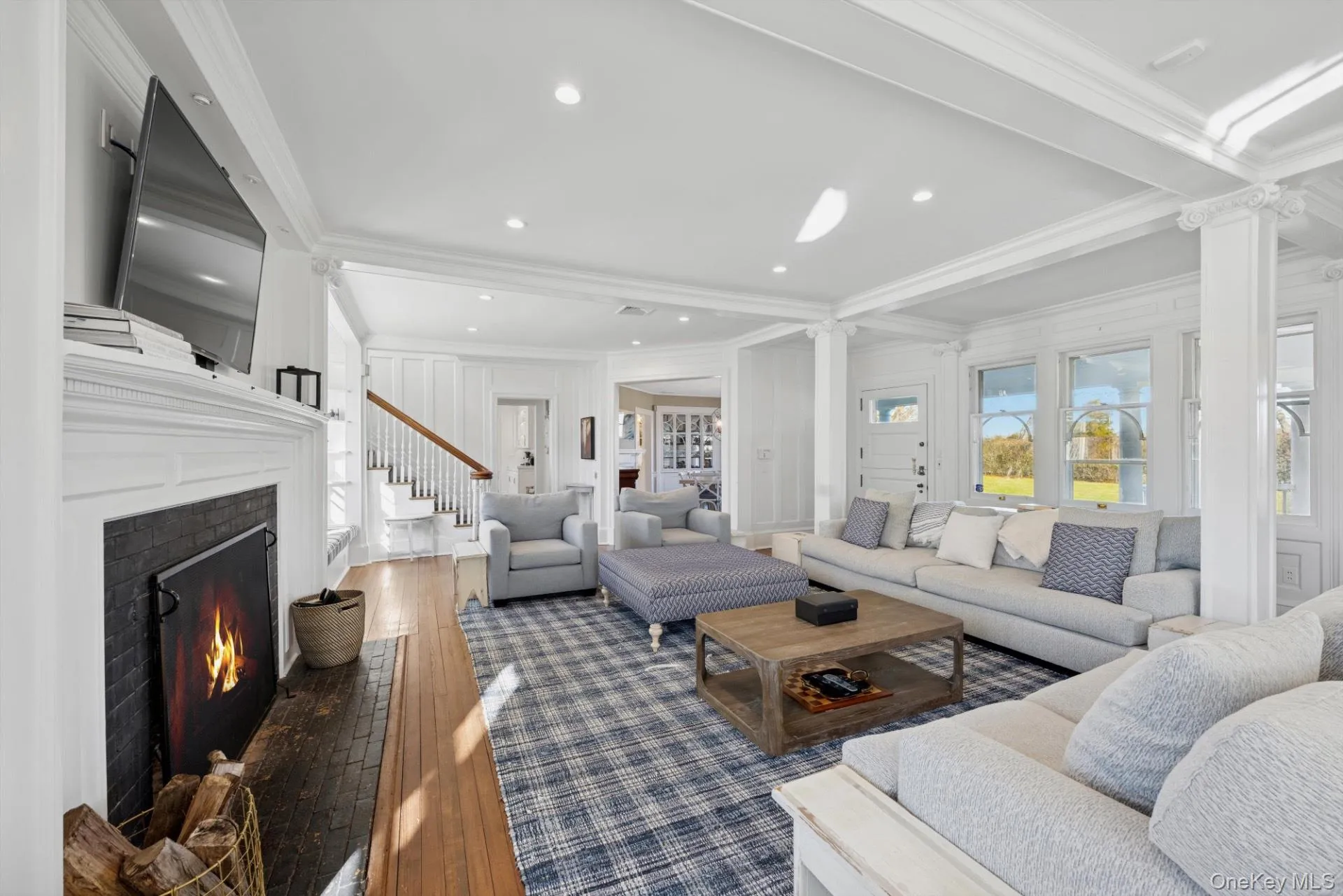Living area with crown molding, a warm lit fireplace, dark wood-type flooring, stairway, and recessed lighting Living area with crown molding, a warm lit fireplace, dark wood-type flooring, stairway, and recessed lighting