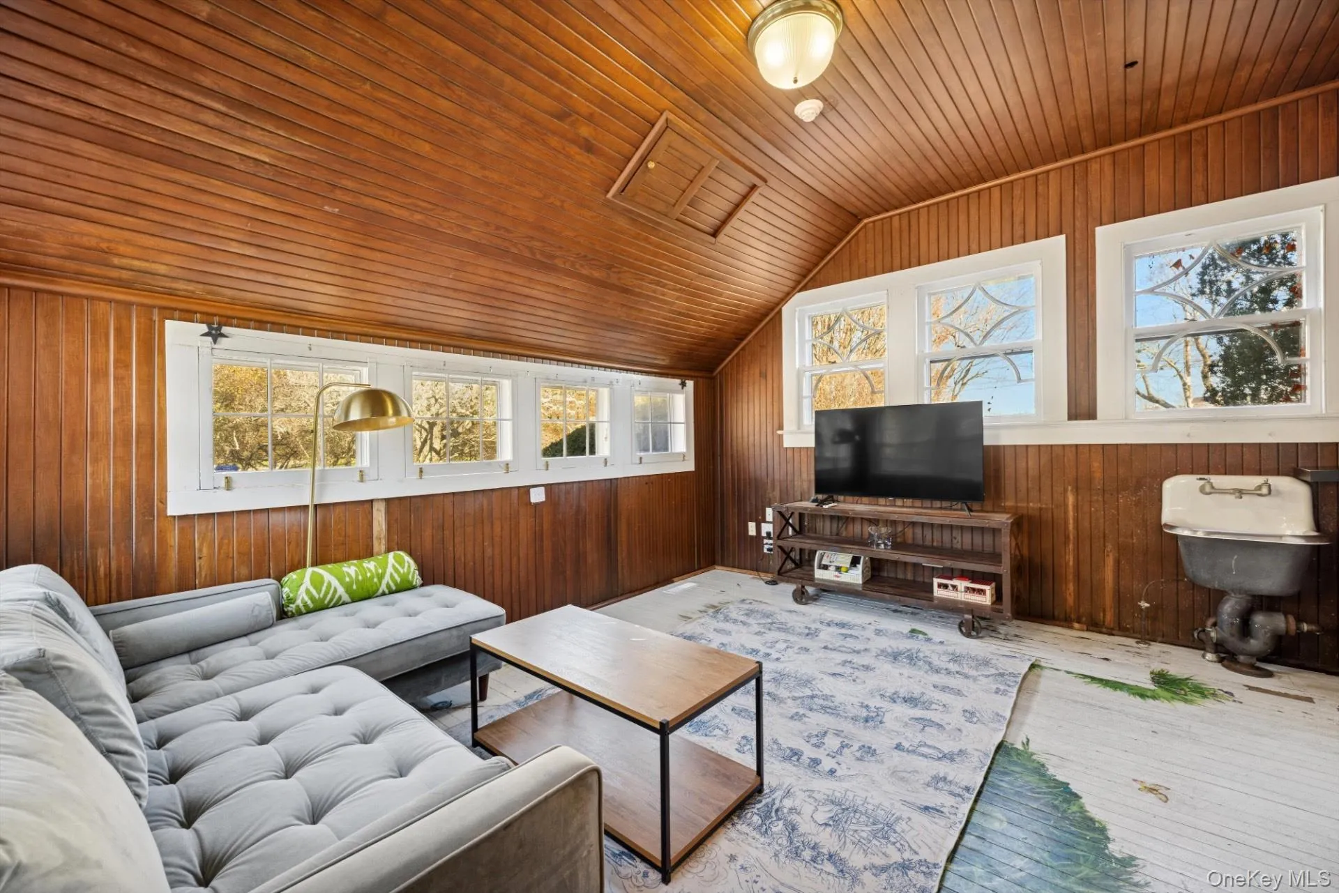 Living area featuring wooden walls, lofted ceiling, wood ceiling, and healthy amount of natural light Living area featuring wooden walls, lofted ceiling, wood ceiling, and healthy amount of natural light