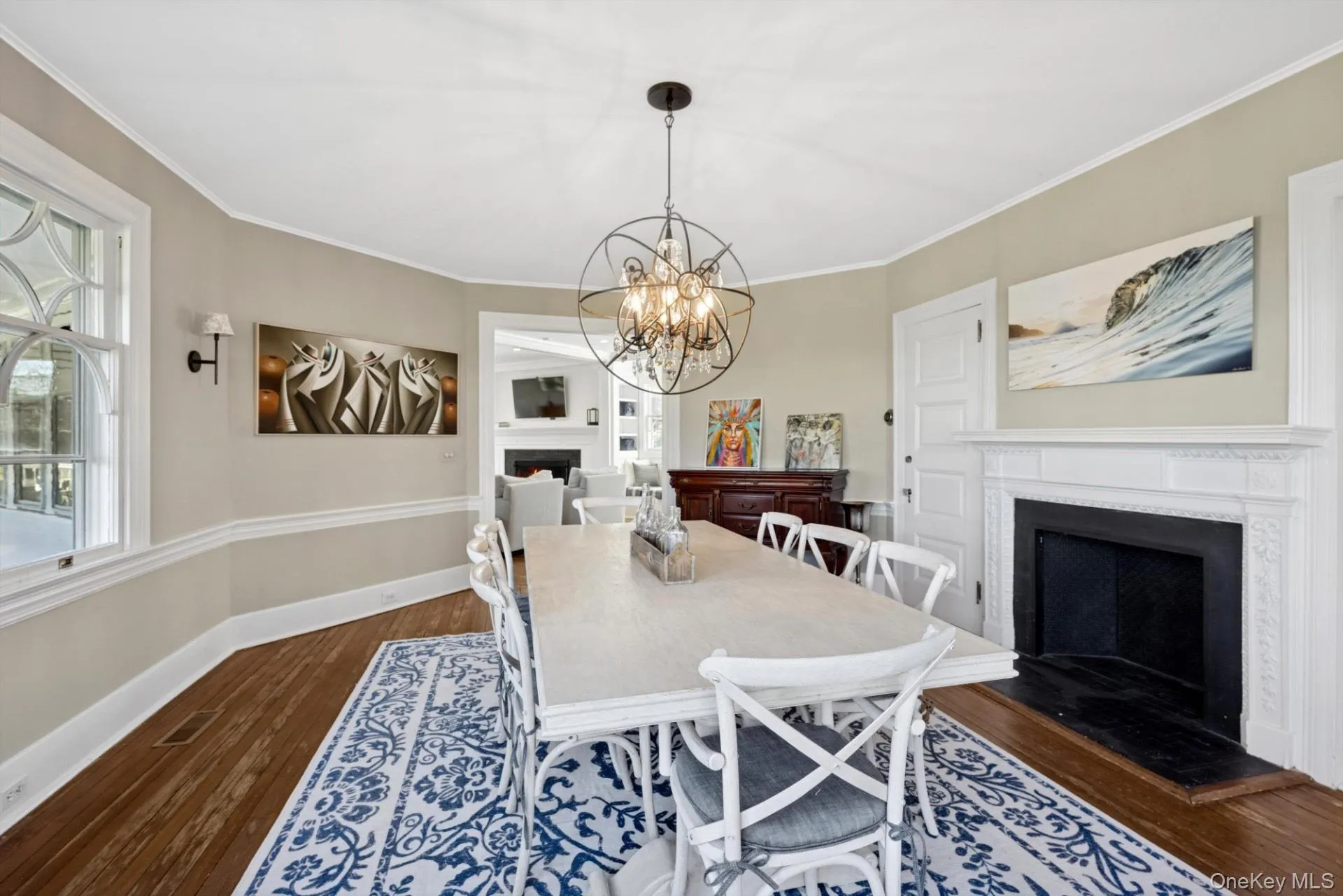 Dining space featuring a fireplace, dark wood-style flooring, ornamental molding, and a chandelier Dining space featuring a fireplace, dark wood-style flooring, ornamental molding, and a chandelier