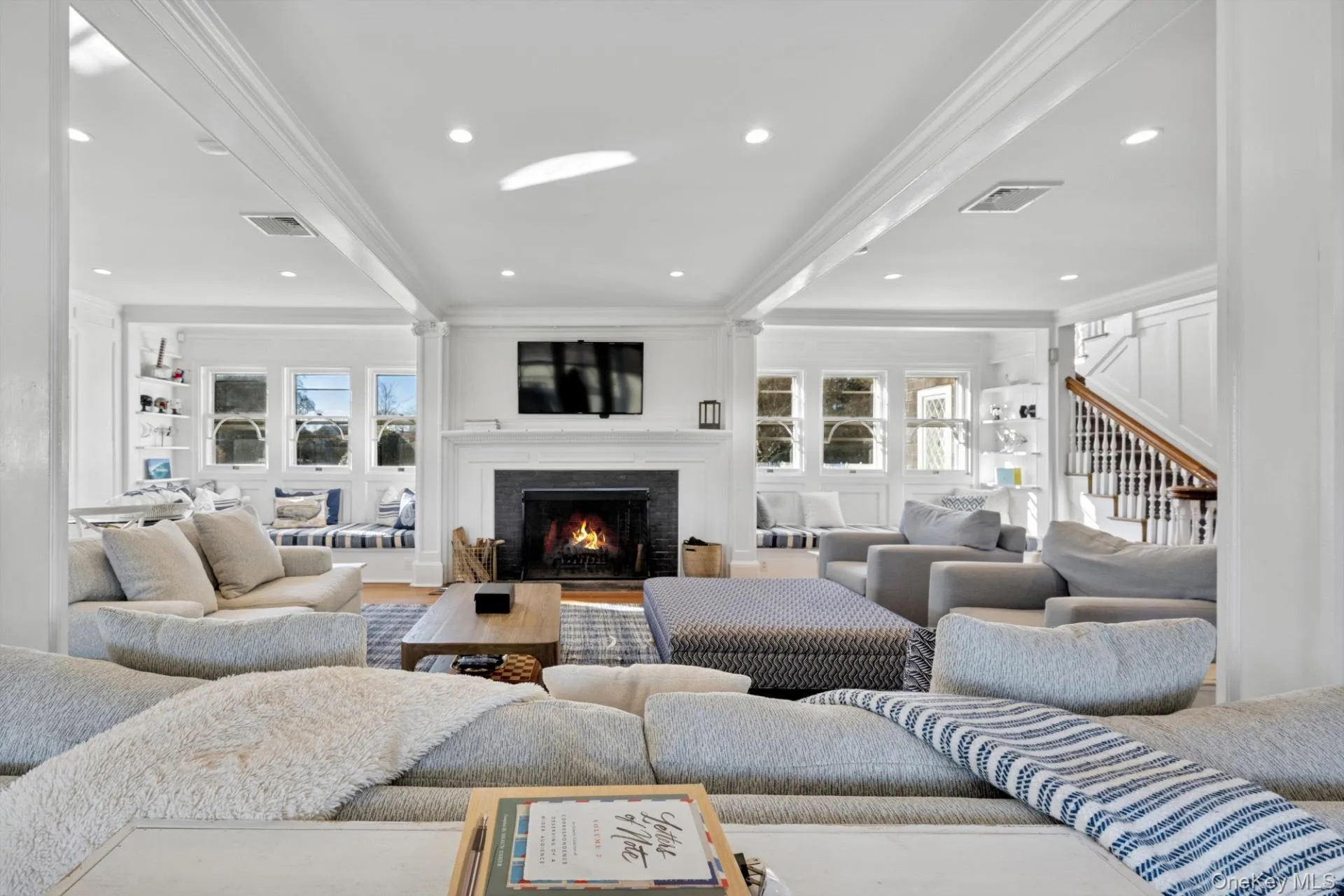Living room with ornamental molding, a lit fireplace, wood finished floors, recessed lighting, and stairway Living room with ornamental molding, a lit fireplace, wood finished floors, recessed lighting, and stairway