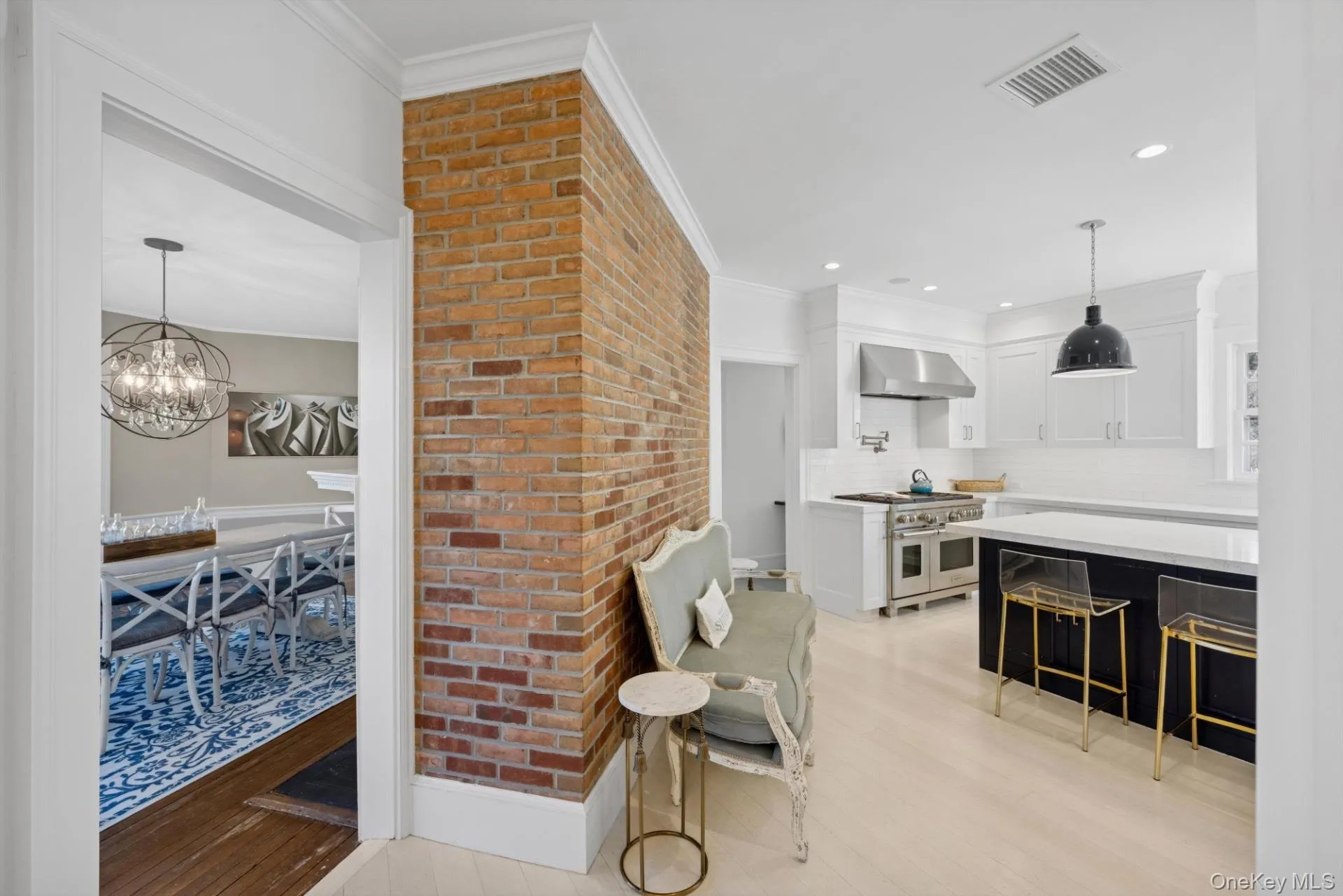 Kitchen with decorative light fixtures, dark cabinetry, white cabinets, light wood-style floors, and range with two ovens Kitchen with decorative light fixtures, dark cabinetry, white cabinets, light wood-style floors, and range with two ovens