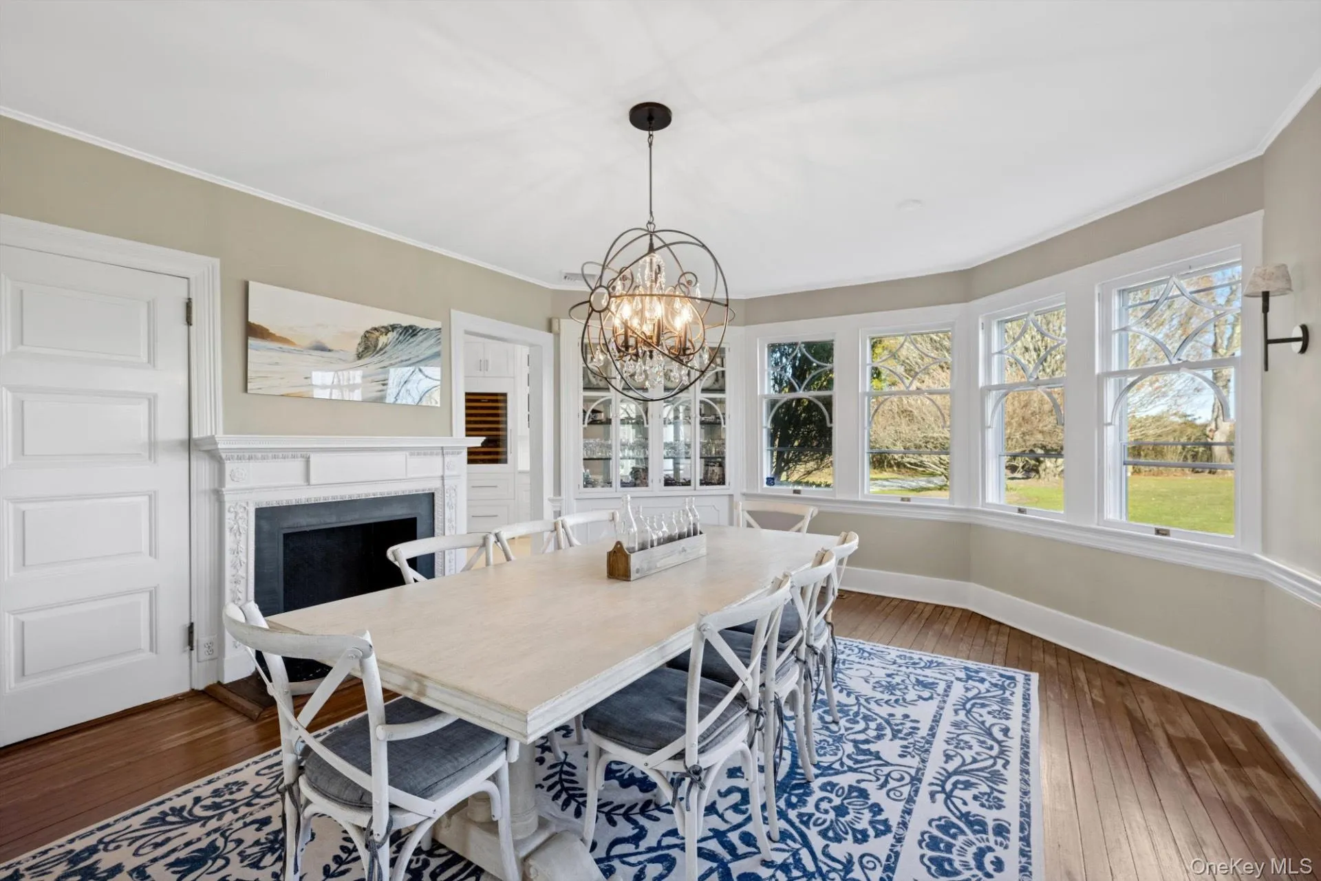 Dining area with dark wood finished floors, crown molding, a chandelier, and a fireplace Dining area with dark wood finished floors, crown molding, a chandelier, and a fireplace