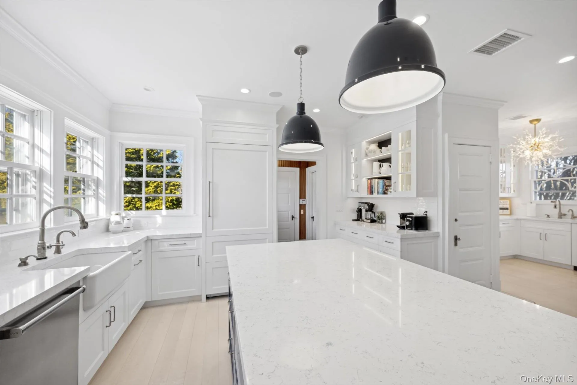 Kitchen featuring hanging light fixtures, white cabinetry, ornamental molding, light stone counters, and stainless steel dishwasher Kitchen featuring hanging light fixtures, white cabinetry, ornamental molding, light stone counters, and stainless steel dishwasher