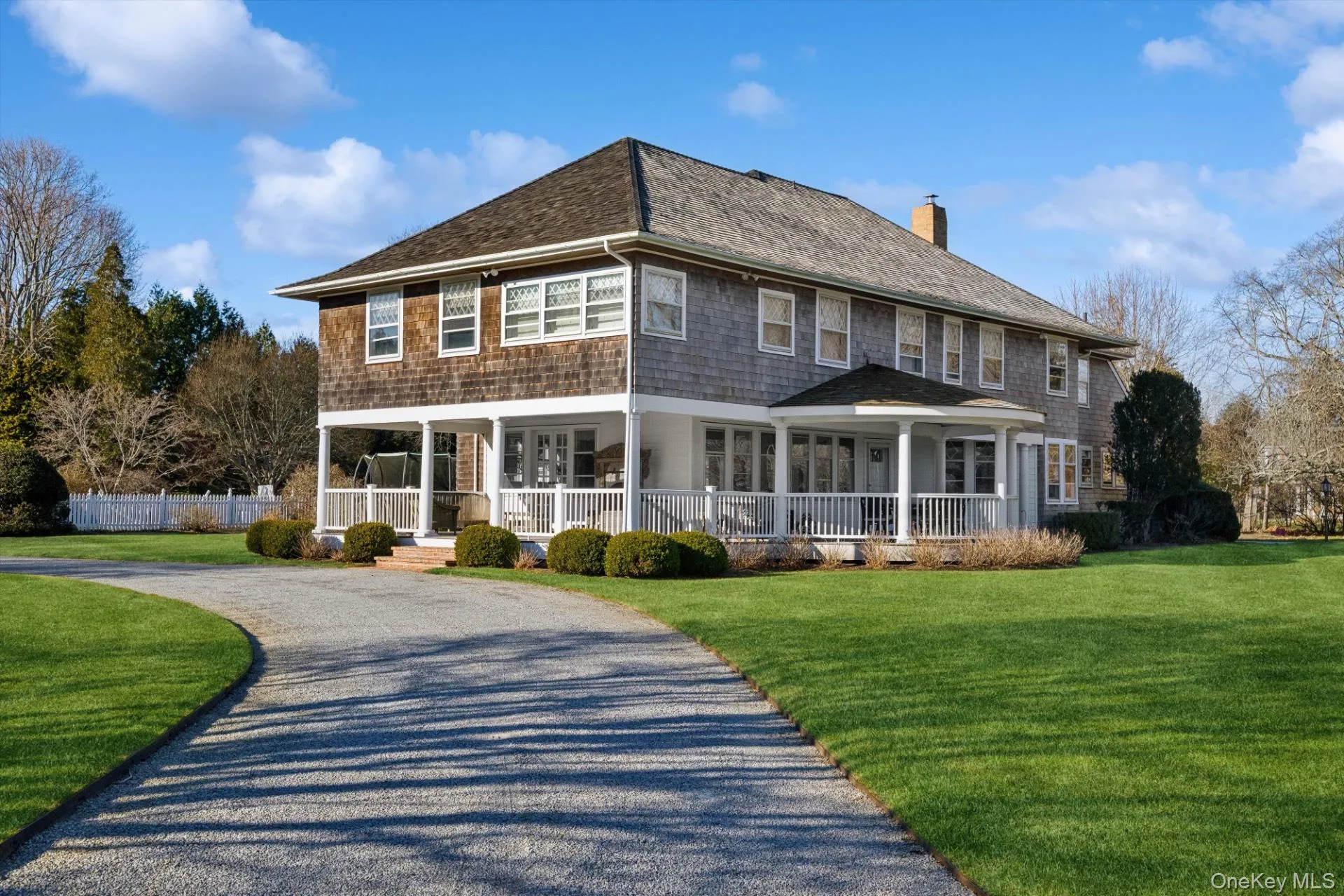 Rear view of house featuring a porch, a chimney, a yard, driveway, and a shingled roof Rear view of house featuring a porch, a chimney, a yard, driveway, and a shingled roof