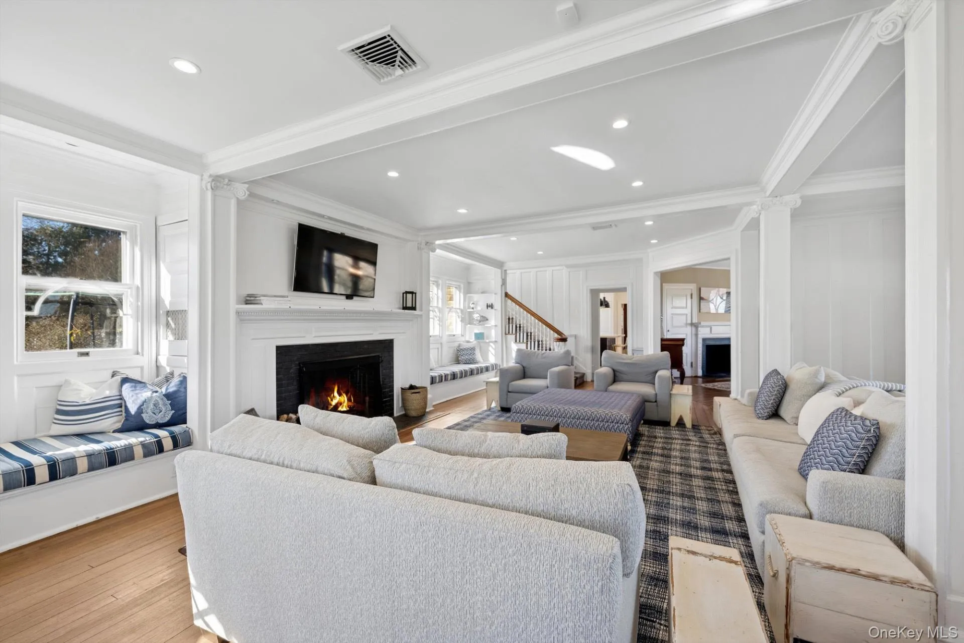 Living area featuring a warm lit fireplace, crown molding, wood-type flooring, and recessed lighting Living area featuring a warm lit fireplace, crown molding, wood-type flooring, and recessed lighting