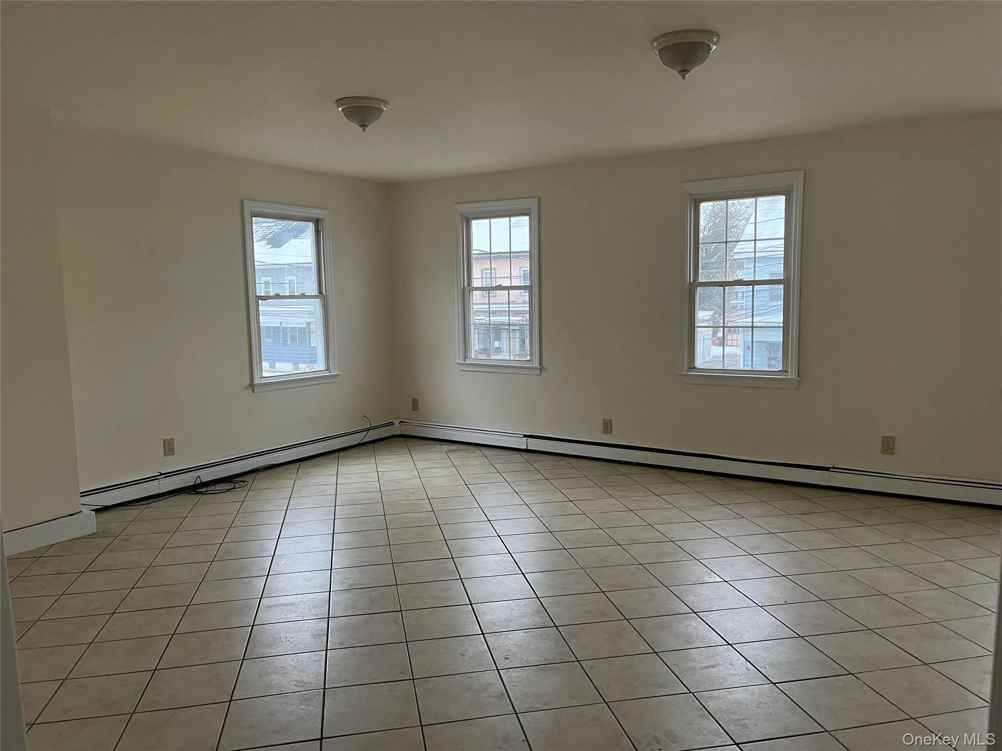 Unfurnished room with plenty of natural light, light tile patterned flooring, and baseboard heating Unfurnished room with plenty of natural light, light tile patterned flooring, and baseboard heating