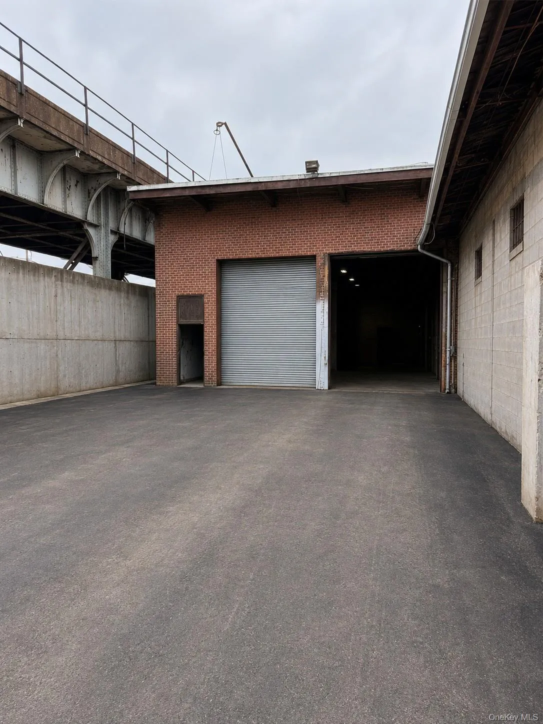Brick exterior building featuring two roll-up doors and an expansive paved lot Brick exterior building featuring two roll-up doors and an expansive paved lot