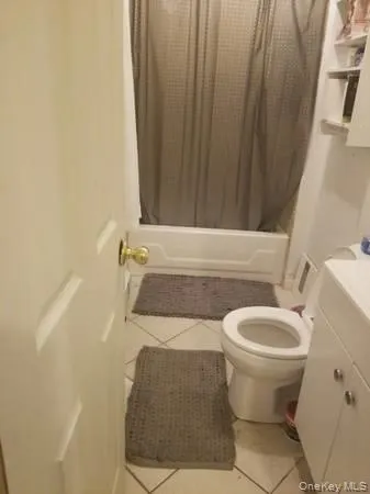 Full bath featuring light tile patterned flooring, vanity, and shower / bathtub combination with curtain Full bath featuring light tile patterned flooring, vanity, and shower / bathtub combination with curtain