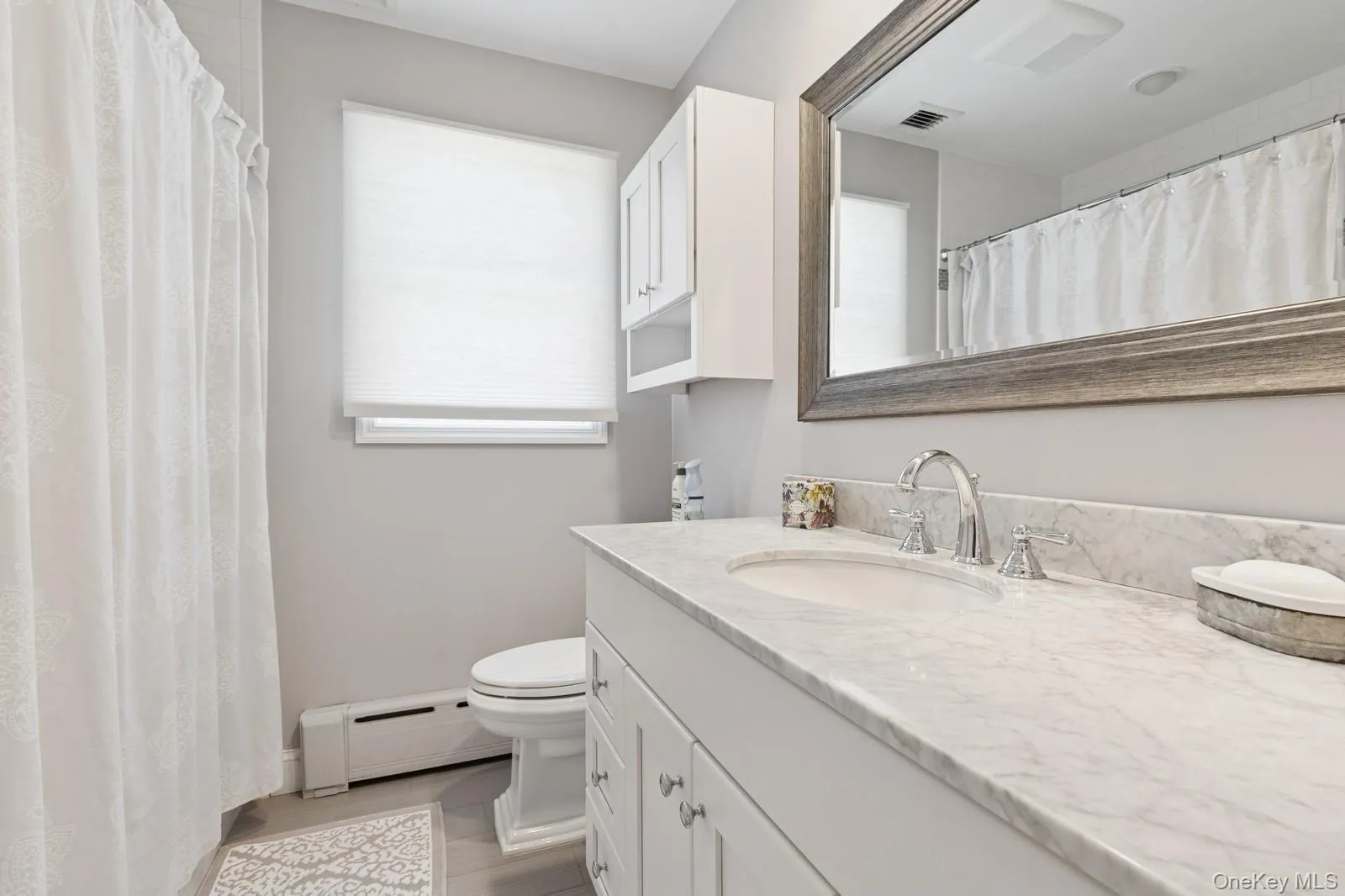 Full bathroom with vanity, a shower with curtain, and a baseboard radiator Full bathroom with vanity, a shower with curtain, and a baseboard radiator