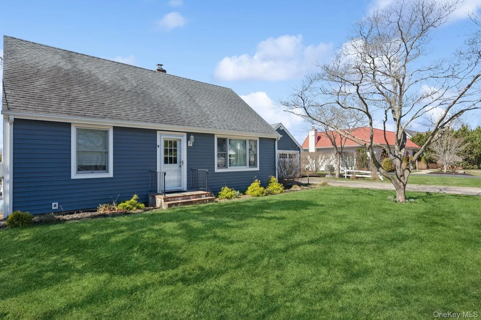 View of front of home featuring a front lawn, a shingled roof, and a chimney View of front of home featuring a front lawn, a shingled roof, and a chimney