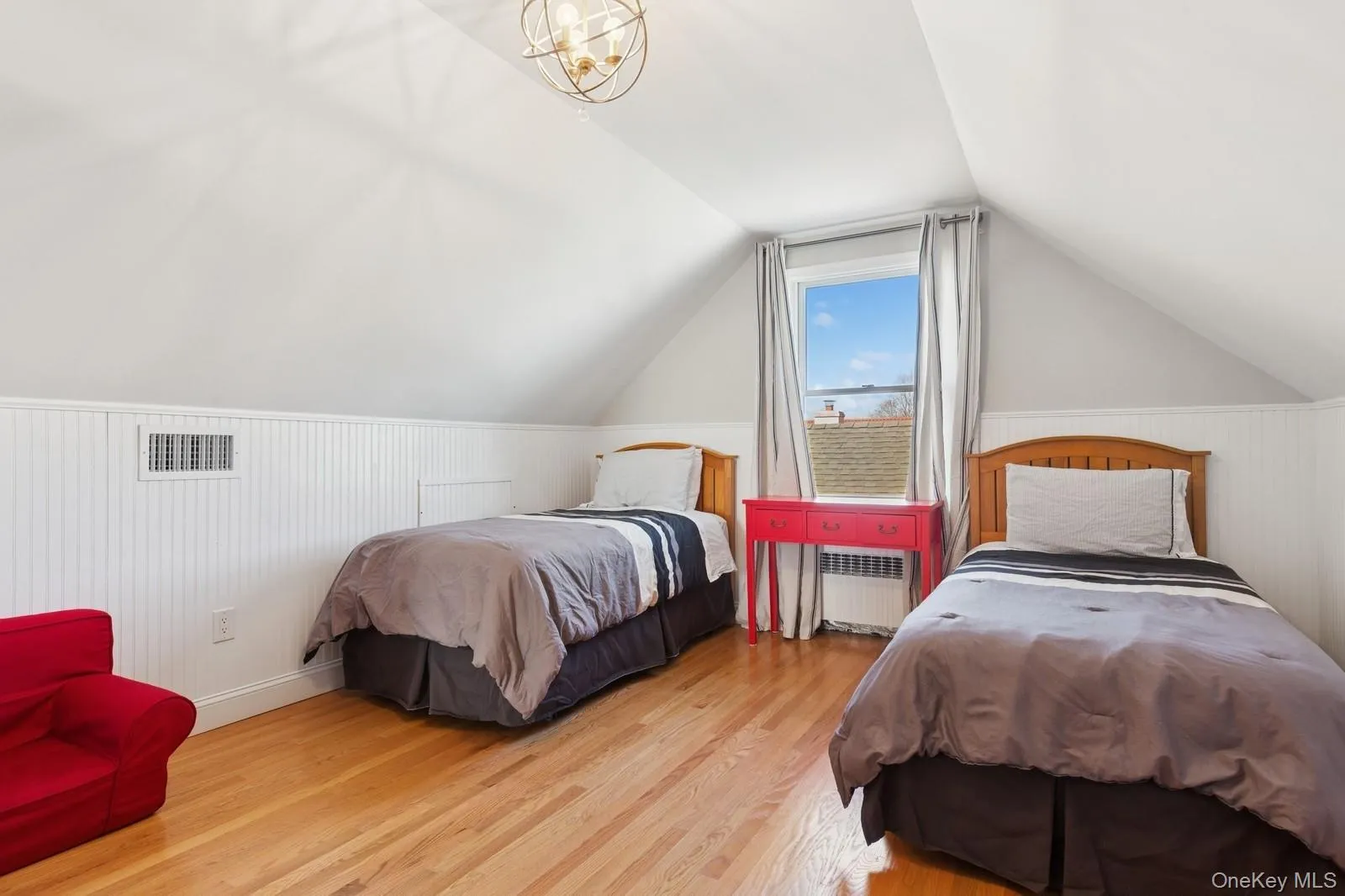 Bedroom featuring vaulted ceiling, radiator heating unit, wood finished floors, wood walls, and a chandelier Bedroom featuring vaulted ceiling, radiator heating unit, wood finished floors, wood walls, and a chandelier
