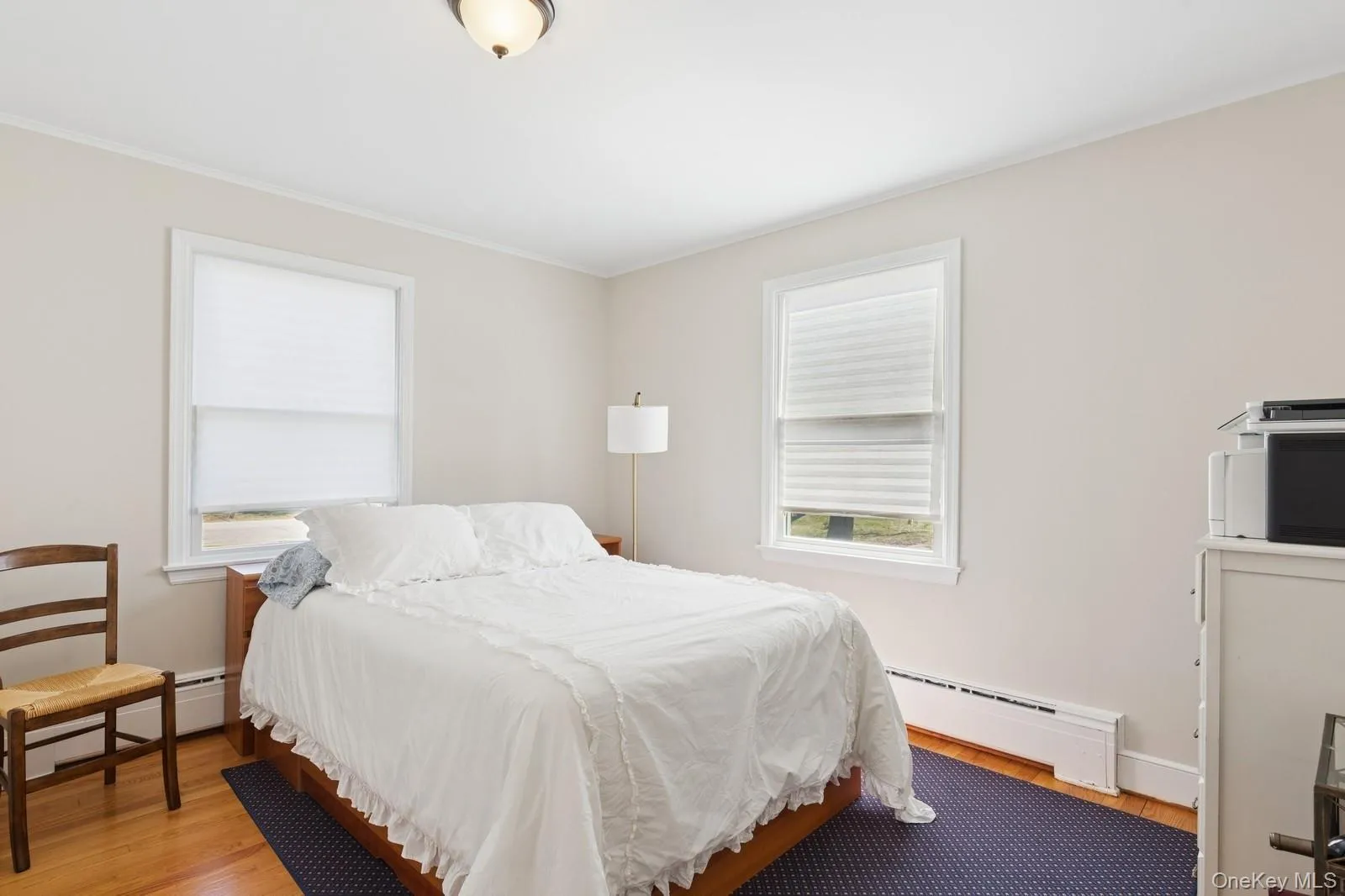 Bedroom with baseboard heating, wood finished floors, and crown molding Bedroom with baseboard heating, wood finished floors, and crown molding