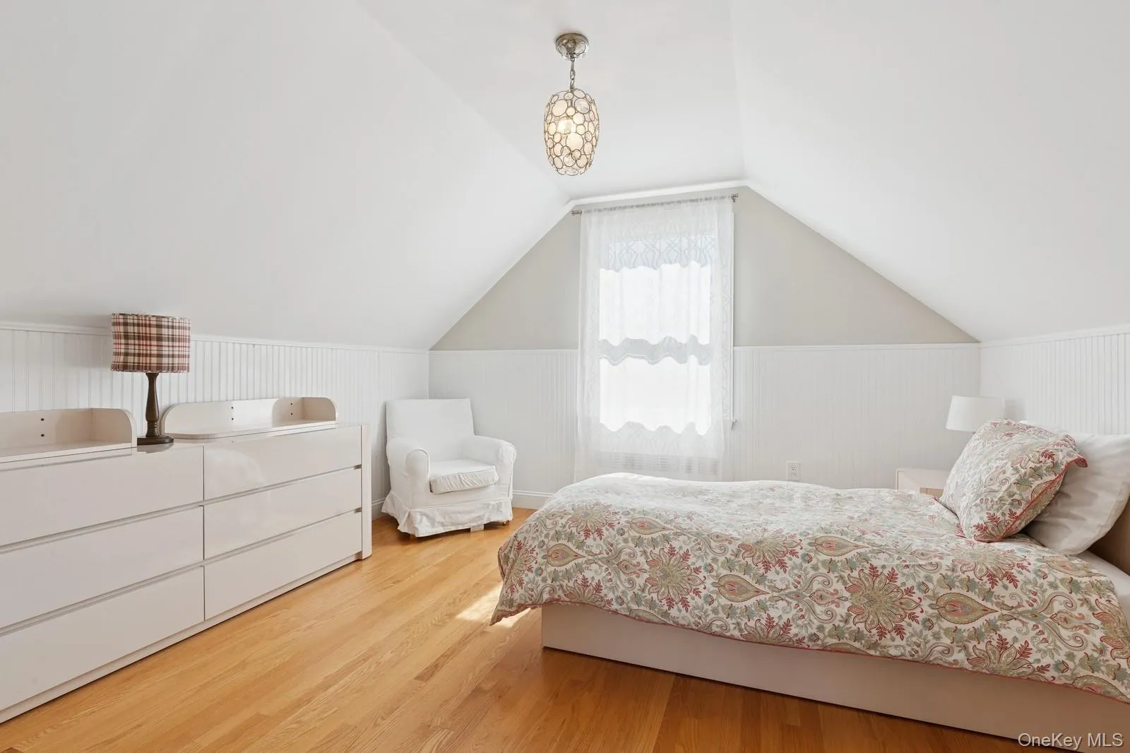 Bedroom featuring wood finished floors, vaulted ceiling, and wainscoting Bedroom featuring wood finished floors, vaulted ceiling, and wainscoting