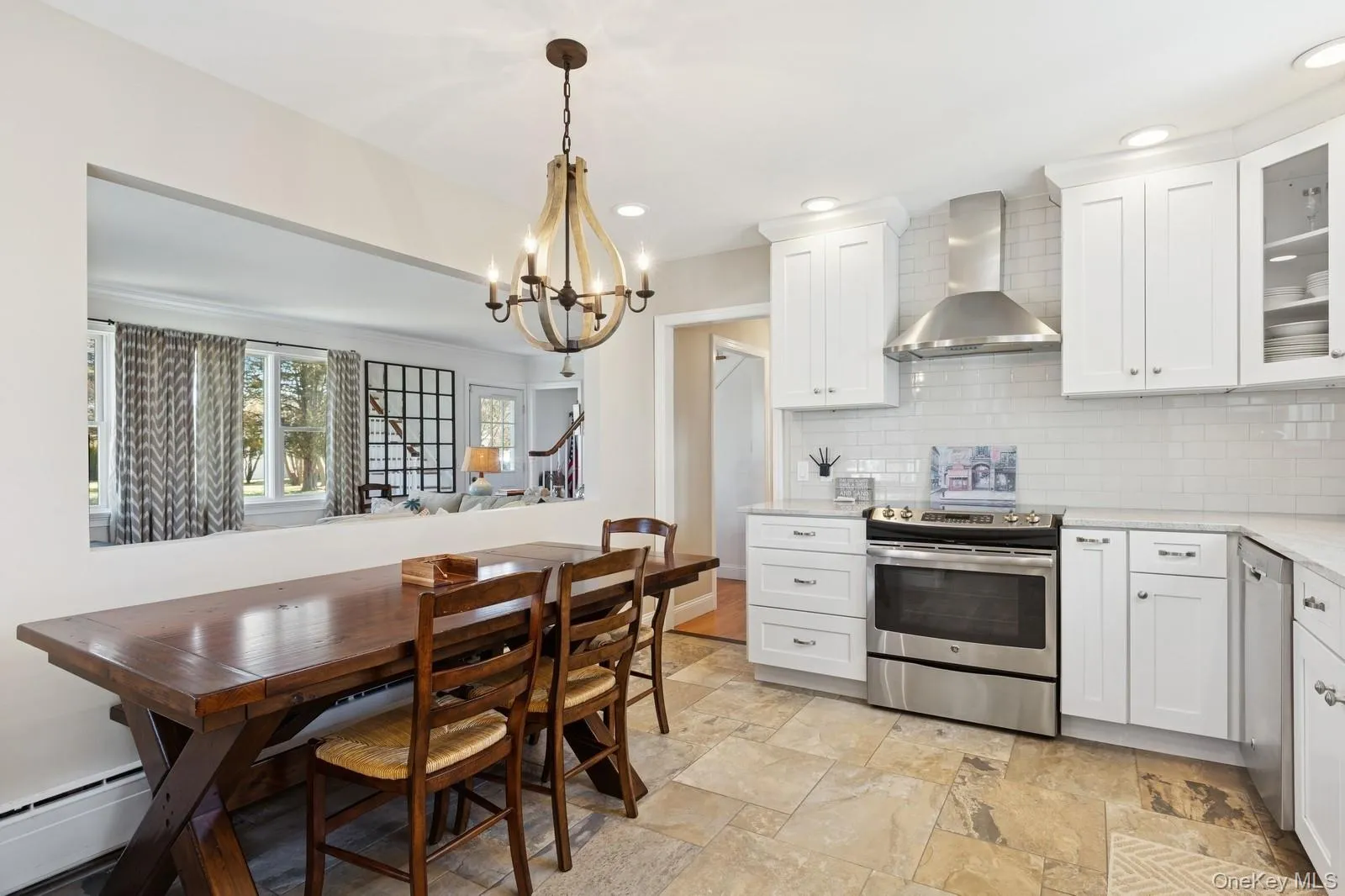 Kitchen featuring stainless steel appliances, wall chimney exhaust hood, white cabinetry, glass insert cabinets, and recessed lighting Kitchen featuring stainless steel appliances, wall chimney exhaust hood, white cabinetry, glass insert cabinets, and recessed lighting