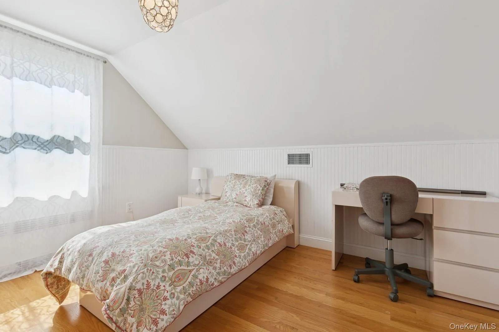 Bedroom featuring lofted ceiling, wood finished floors, radiator, a wainscoted wall, and a desk Bedroom featuring lofted ceiling, wood finished floors, radiator, a wainscoted wall, and a desk