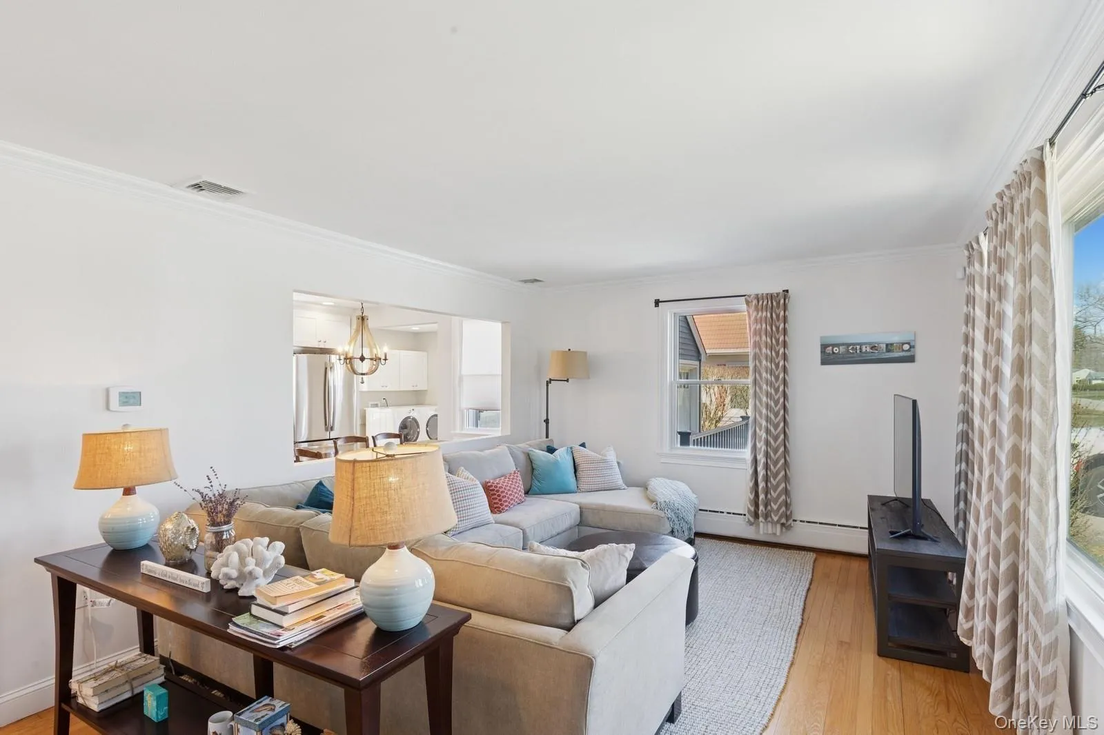Living area featuring crown molding, light wood-style flooring, a chandelier, and a baseboard radiator Living area featuring crown molding, light wood-style flooring, a chandelier, and a baseboard radiator