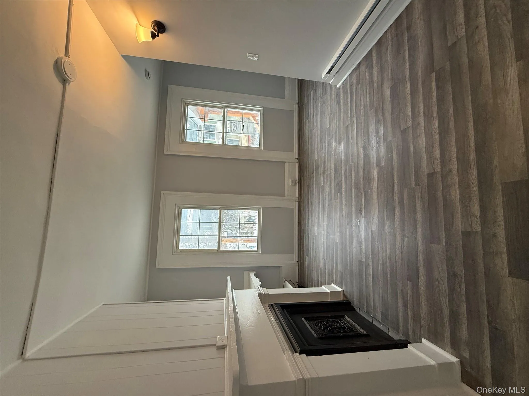 Unfurnished living room with a fireplace, dark wood finished floors, a baseboard heating unit, and healthy amount of natural light Unfurnished living room with a fireplace, dark wood finished floors, a baseboard heating unit, and healthy amount of natural light