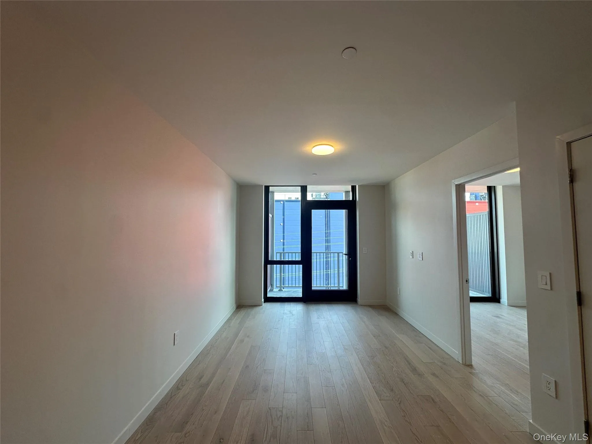 Empty room with baseboards, a wall of windows, and light wood-style floors Empty room with baseboards, a wall of windows, and light wood-style floors