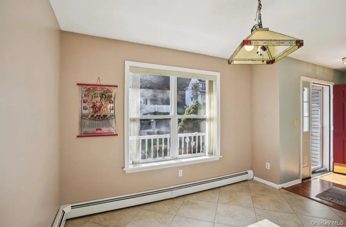 Unfurnished dining area with a baseboard radiator and light tile patterned flooring Unfurnished dining area with a baseboard radiator and light tile patterned flooring