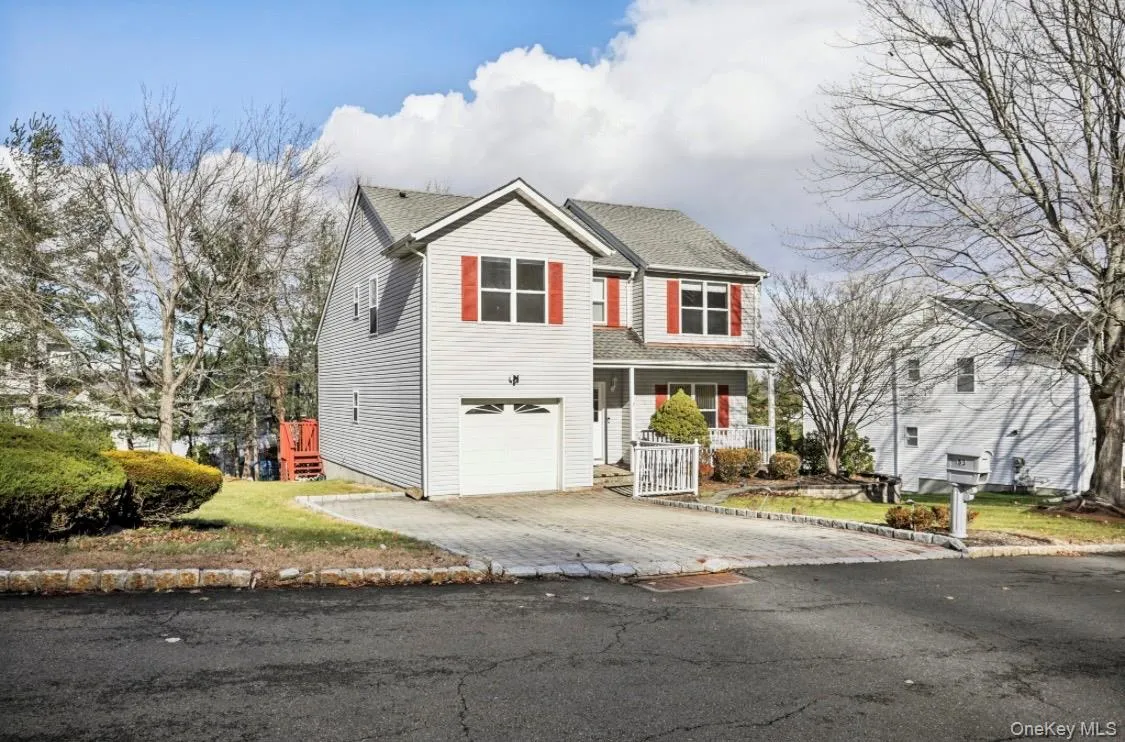 Traditional home featuring covered porch, driveway, and a garage Traditional home featuring covered porch, driveway, and a garage