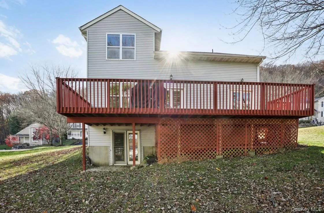 Rear view of property featuring a wooden deck and a lawn Rear view of property featuring a wooden deck and a lawn