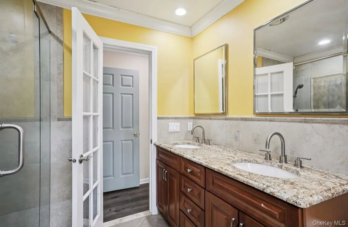 Bathroom with a stall shower, crown molding, double vanity, recessed lighting, and light wood-style flooring Bathroom with a stall shower, crown molding, double vanity, recessed lighting, and light wood-style flooring