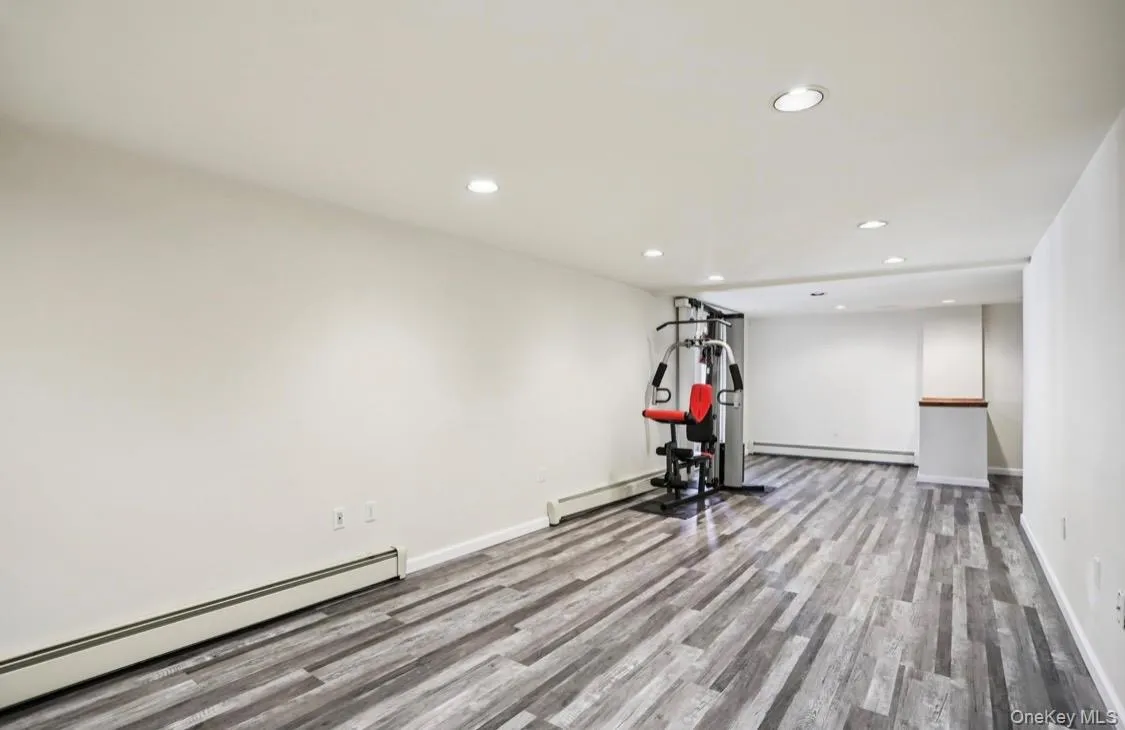 Exercise room featuring a baseboard radiator, recessed lighting, light wood finished floors, and a baseboard heating unit Exercise room featuring a baseboard radiator, recessed lighting, light wood finished floors, and a baseboard heating unit