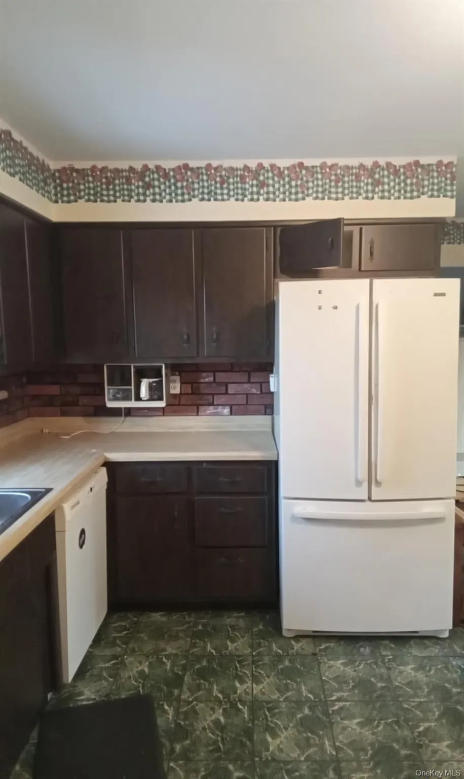 Kitchen with dark brown cabinets, white appliances, and light countertops Kitchen with dark brown cabinets, white appliances, and light countertops