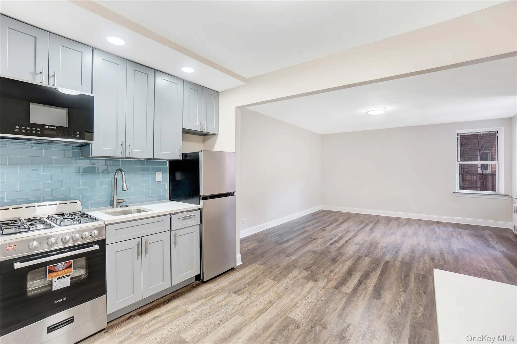 Kitchen featuring appliances with stainless steel finishes, tasteful backsplash, light wood-style flooring, light stone countertops, and open floor plan Kitchen featuring appliances with stainless steel finishes, tasteful backsplash, light wood-style flooring, light stone countertops, and open floor plan