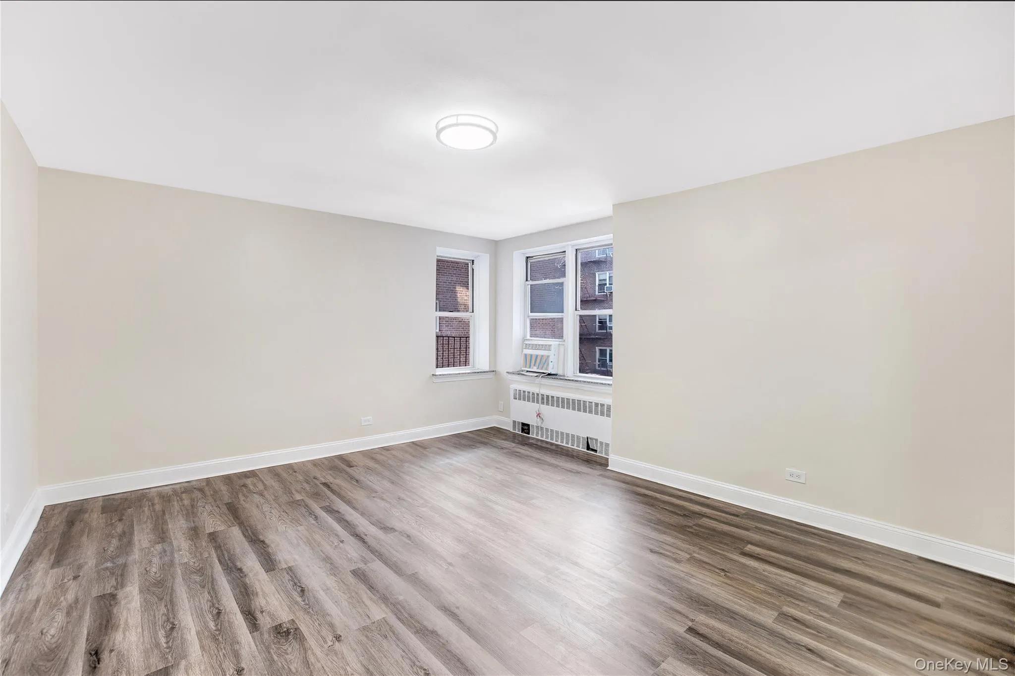 Unfurnished room featuring radiator heating unit and light wood-style flooring Unfurnished room featuring radiator heating unit and light wood-style flooring