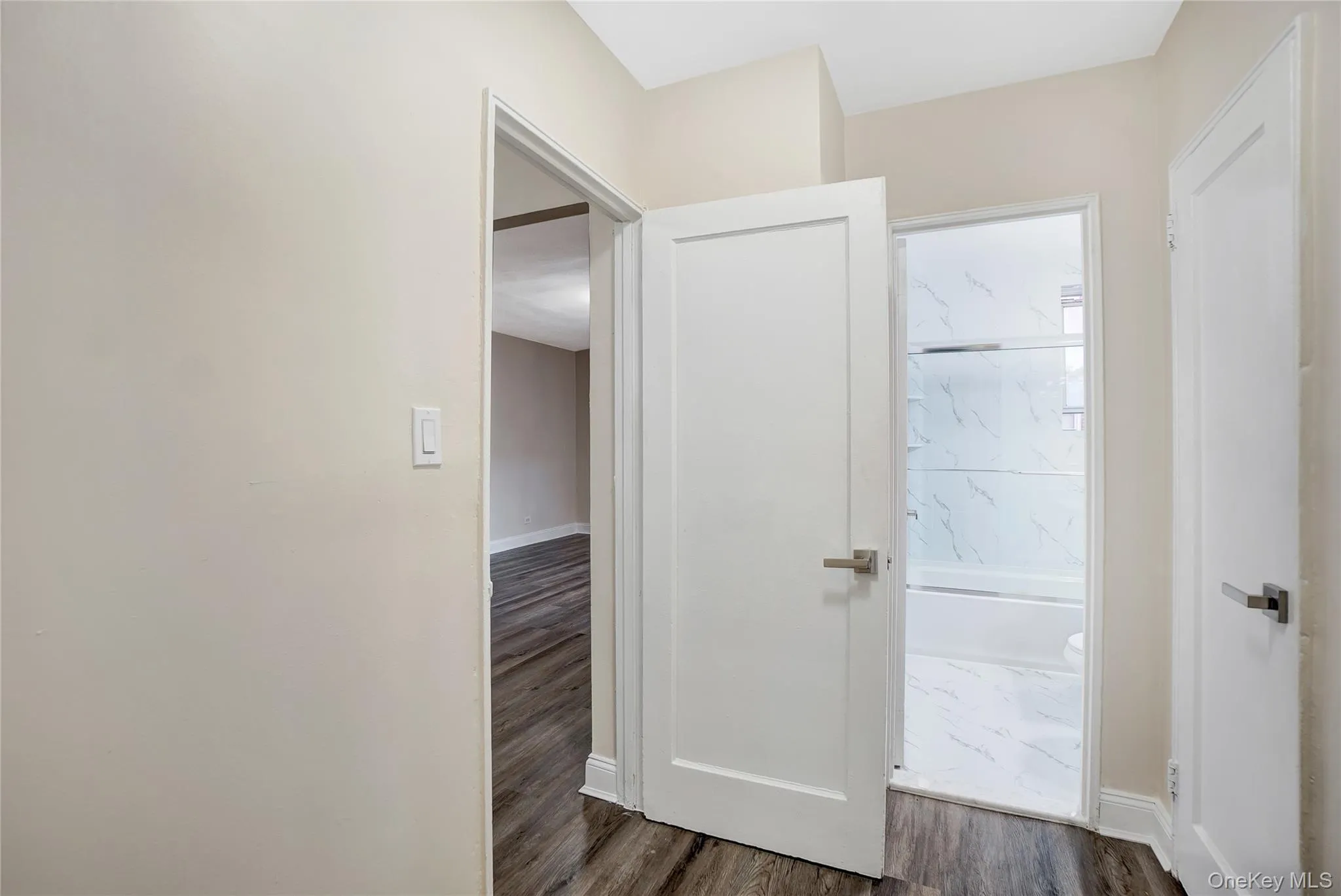 Hallway with dark wood-style flooring and baseboards Hallway with dark wood-style flooring and baseboards