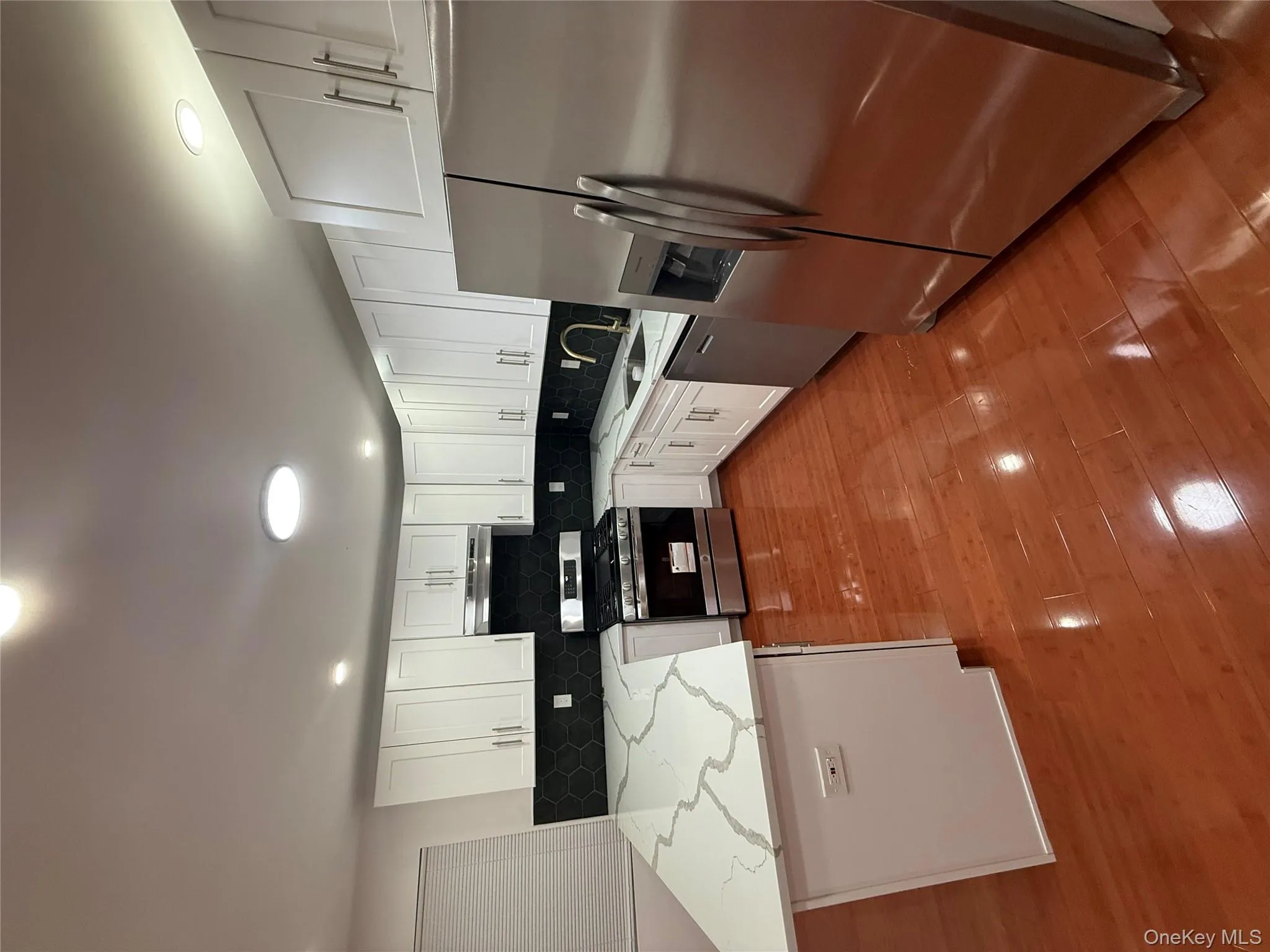 Kitchen with stainless steel appliances, a peninsula, light stone countertops, white cabinetry, and recessed lighting Kitchen with stainless steel appliances, a peninsula, light stone countertops, white cabinetry, and recessed lighting