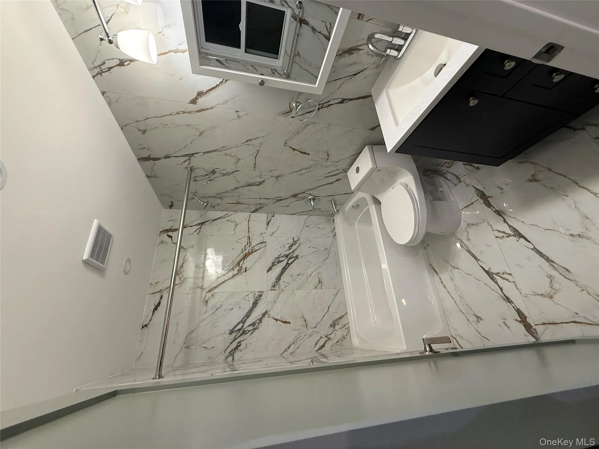 Bathroom with light marble finish floors, stone wall, vanity, a combined bath / shower with marble appearance, and tile walls Bathroom with light marble finish floors, stone wall, vanity, a combined bath / shower with marble appearance, and tile walls