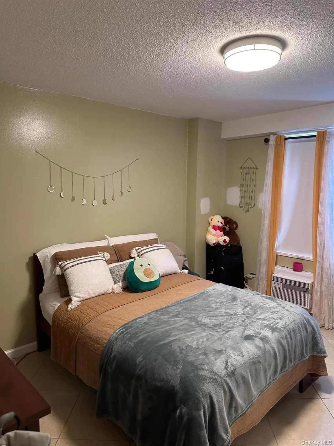 Bedroom featuring light tile patterned floors and a textured ceiling Bedroom featuring light tile patterned floors and a textured ceiling