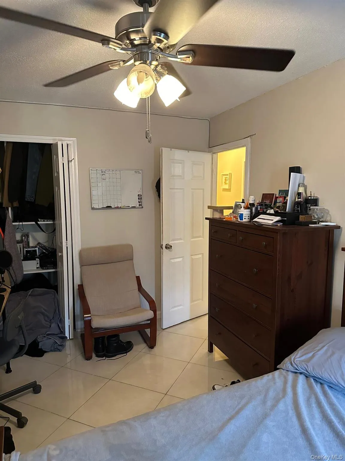 Bedroom with light tile patterned flooring, ceiling fan, and a textured ceiling Bedroom with light tile patterned flooring, ceiling fan, and a textured ceiling