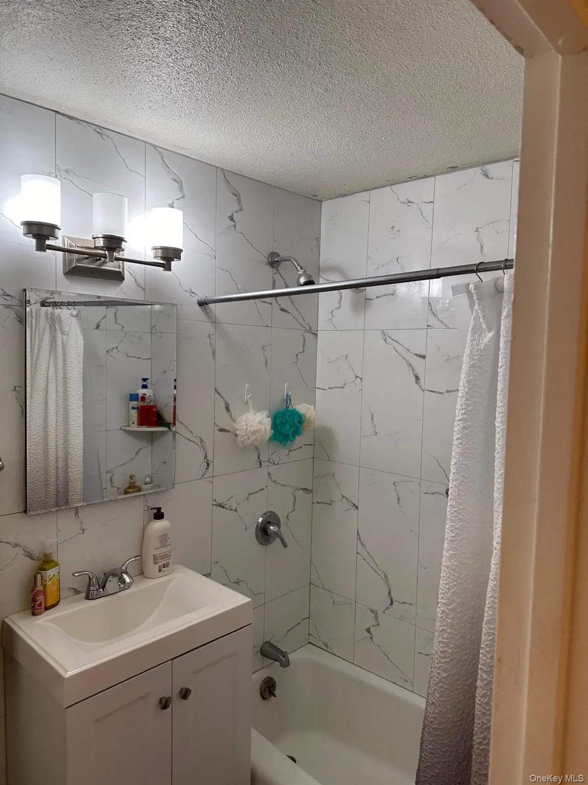 Full bath with shower / tub combo, vanity, and a textured ceiling Full bath with shower / tub combo, vanity, and a textured ceiling
