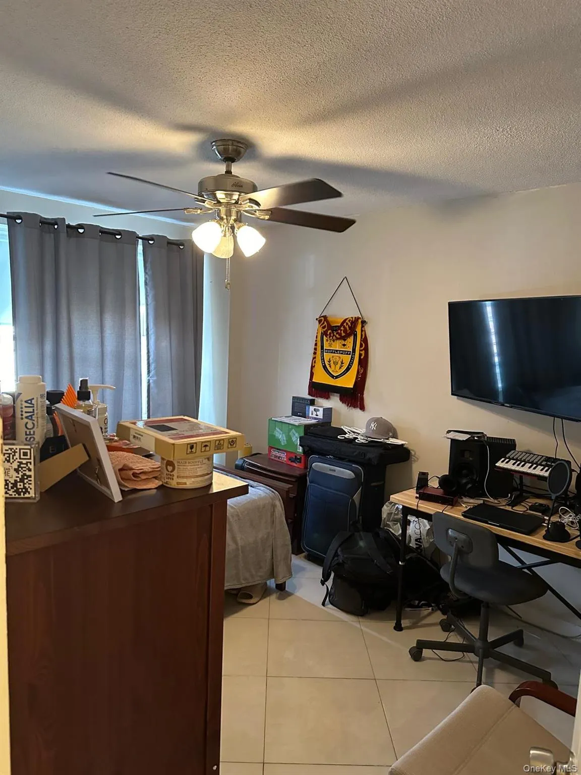 Bedroom featuring light tile patterned flooring, a desk, a textured ceiling, and a ceiling fan Bedroom featuring light tile patterned flooring, a desk, a textured ceiling, and a ceiling fan